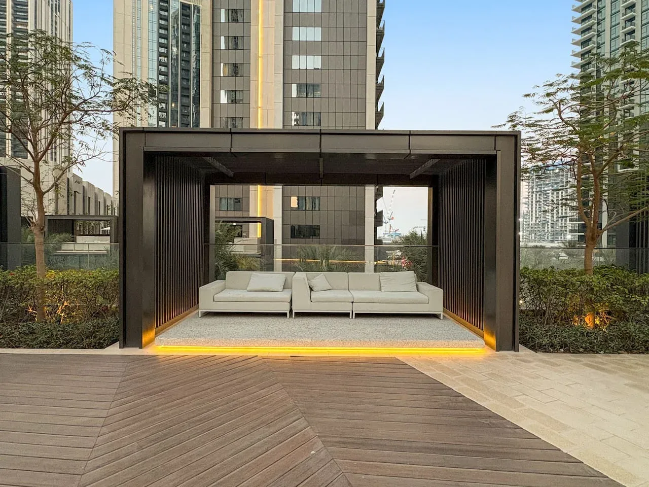 Una zona de estar al aire libre con un pabellón moderno y bancos acolchados.