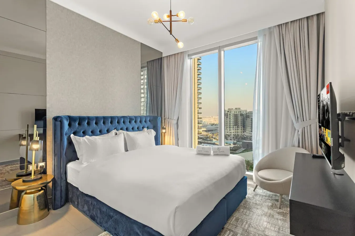 Un dormitorio con una cama frente a grandes ventanas con vistas a la ciudad.