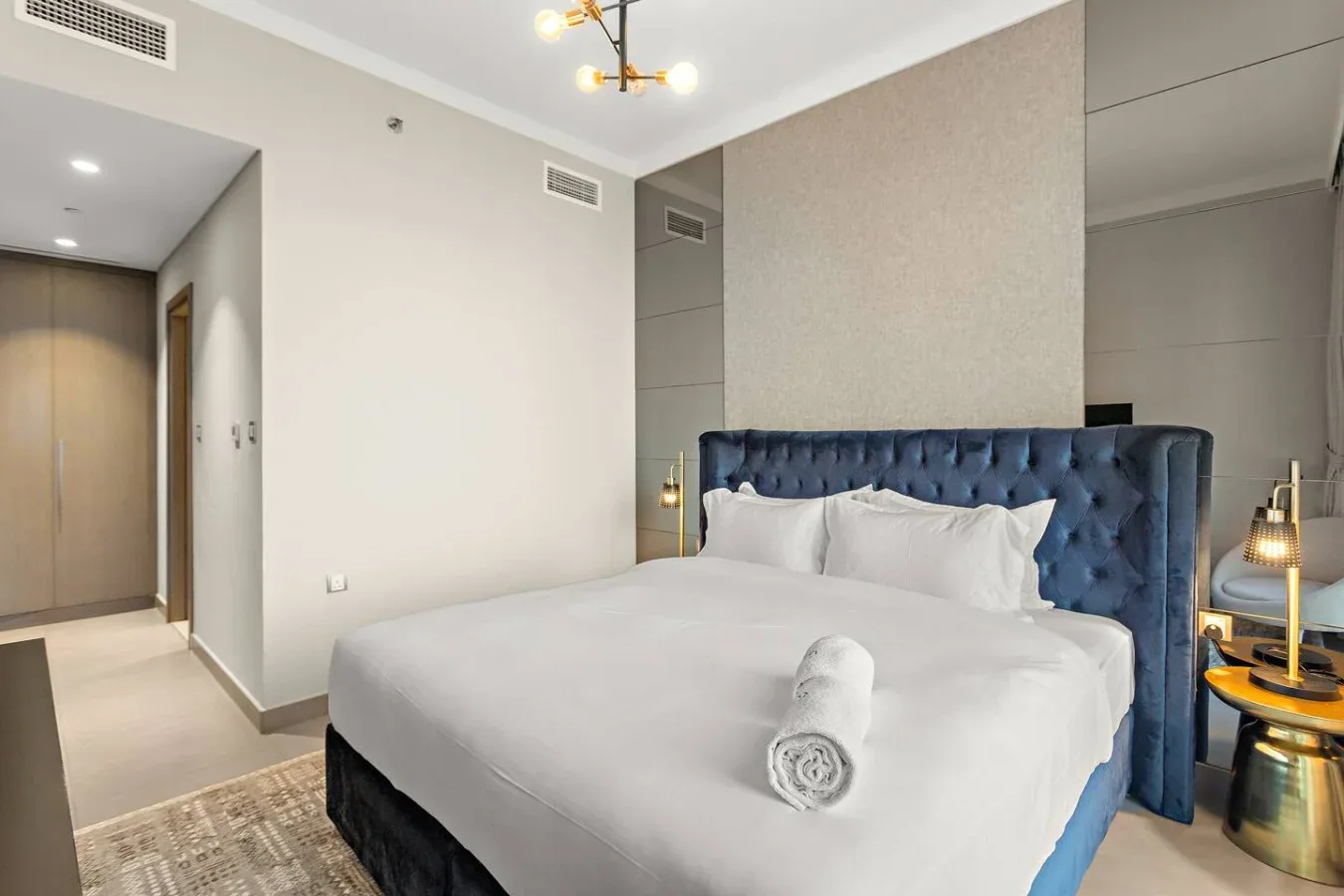 Un dormitorio con una cama tendida y un cabecero tapizado azul oscuro.