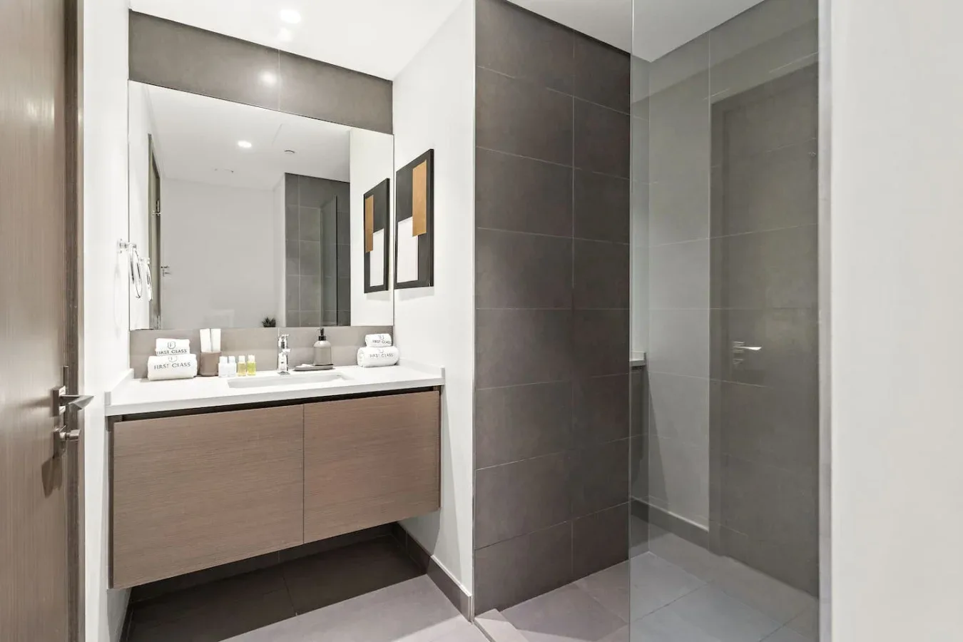 Un baño moderno con lavabo suspendido, espejo amplio y ducha de vidrio.