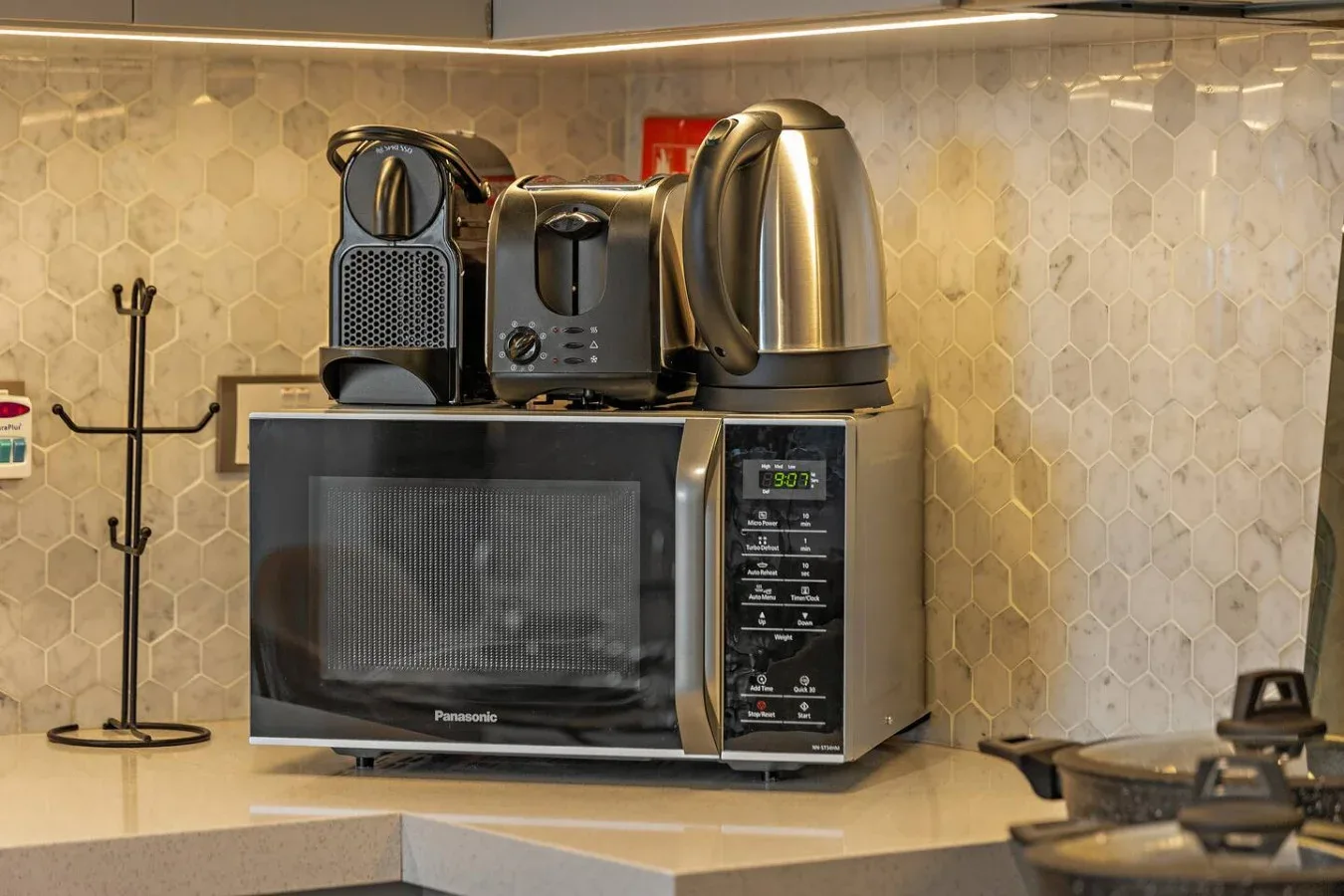 Una encimera de cocina con pequeños electrodomésticos está junto a un salpicadero de azulejos.