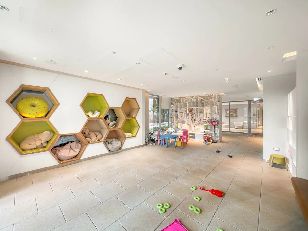 Una zona de juegos interior luminosa tiene nichos de colores y juguetes dispersos.