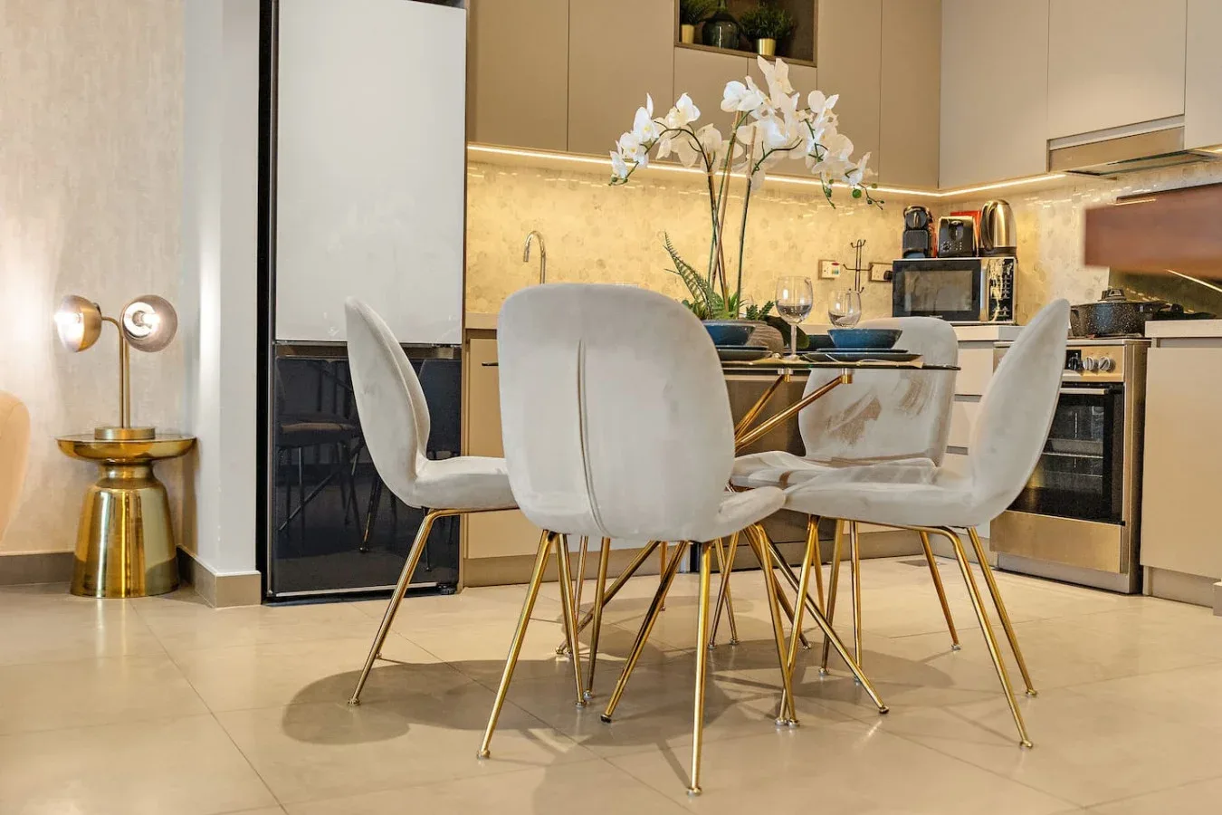 Un comedor con asientos blancos junto a una cocina moderna.