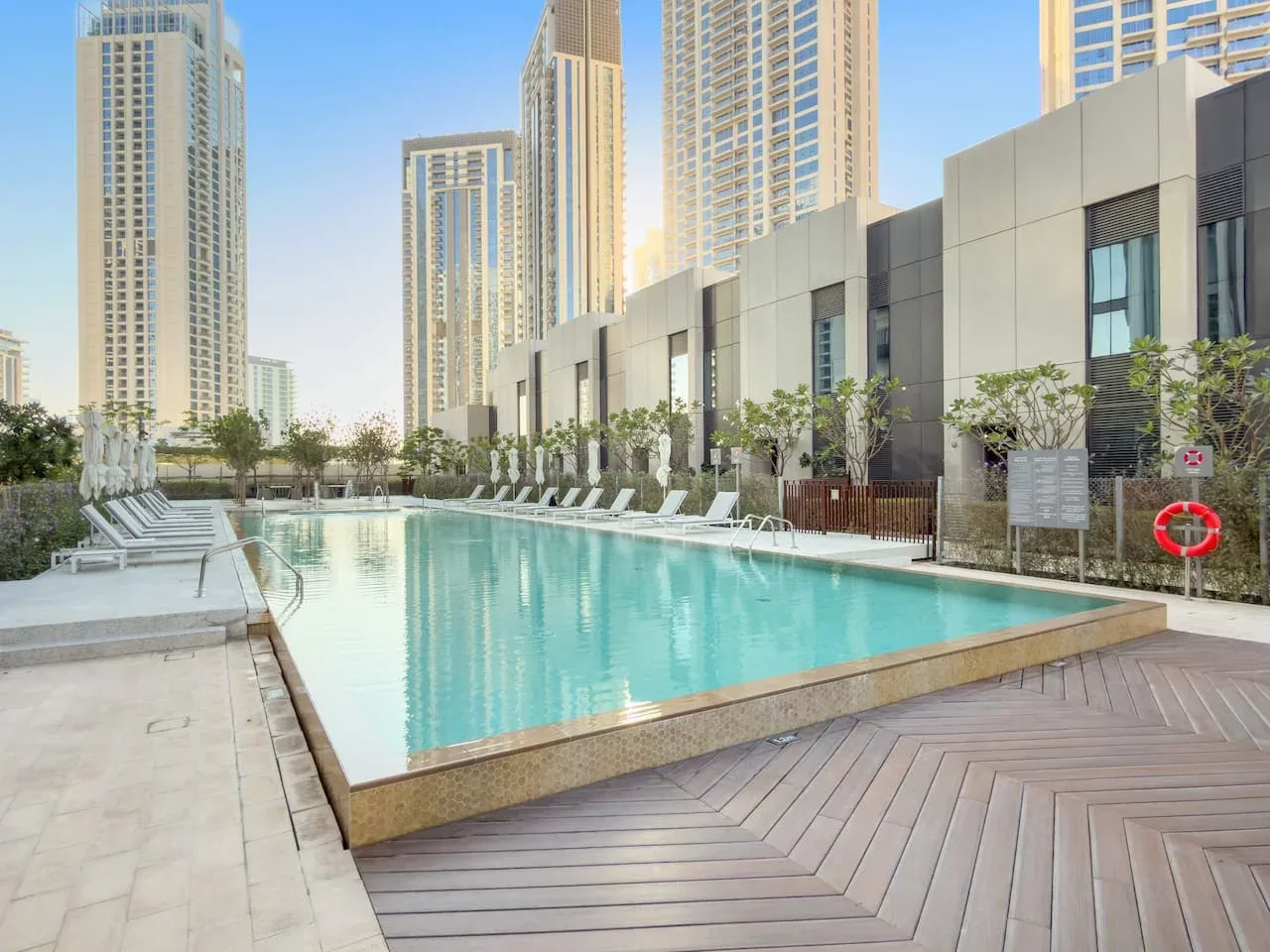Una piscina al aire libre está rodeada de tumbonas y edificios altos.