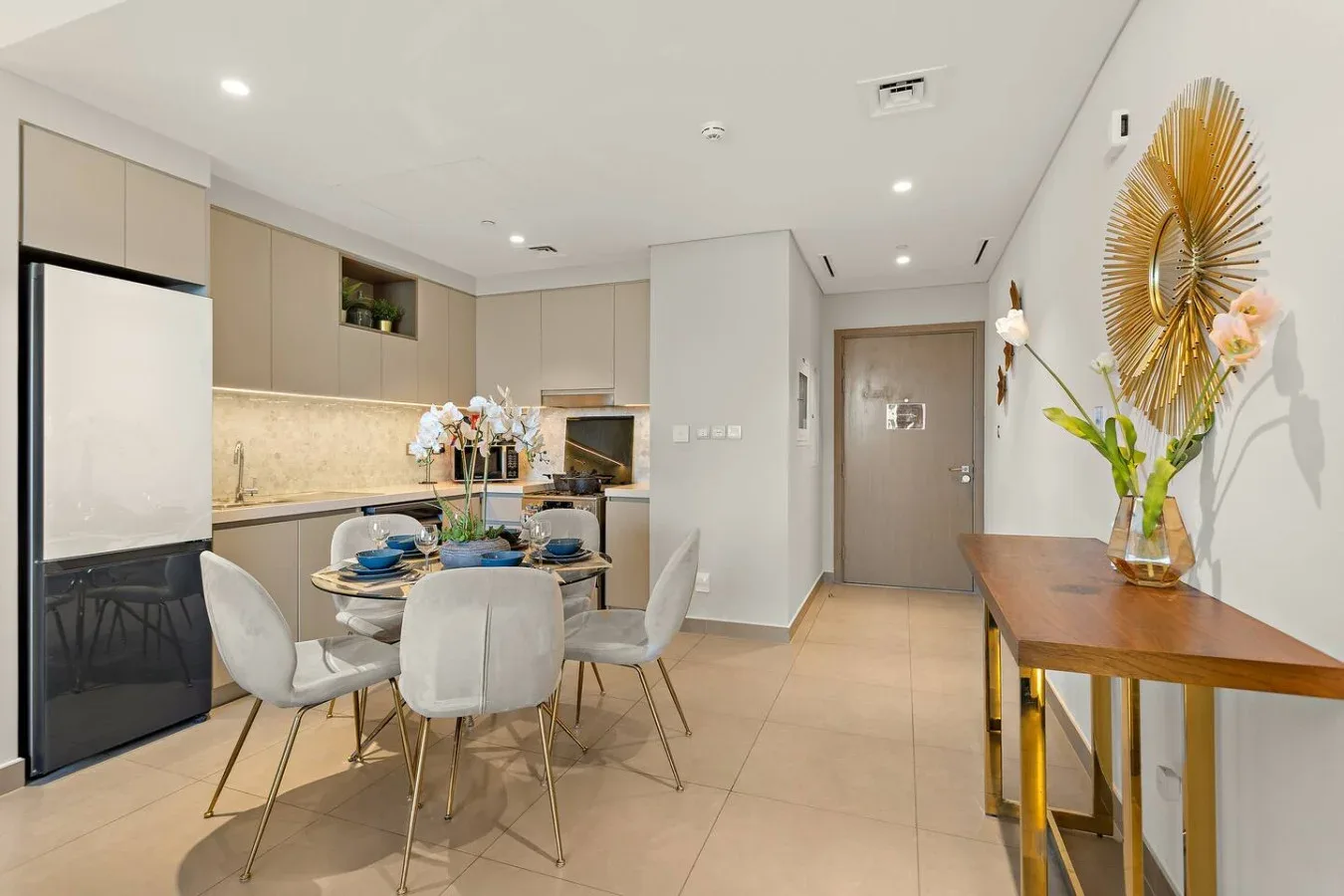 Una cocina moderna y comedor dan a un pasillo, con una mesa y asientos.