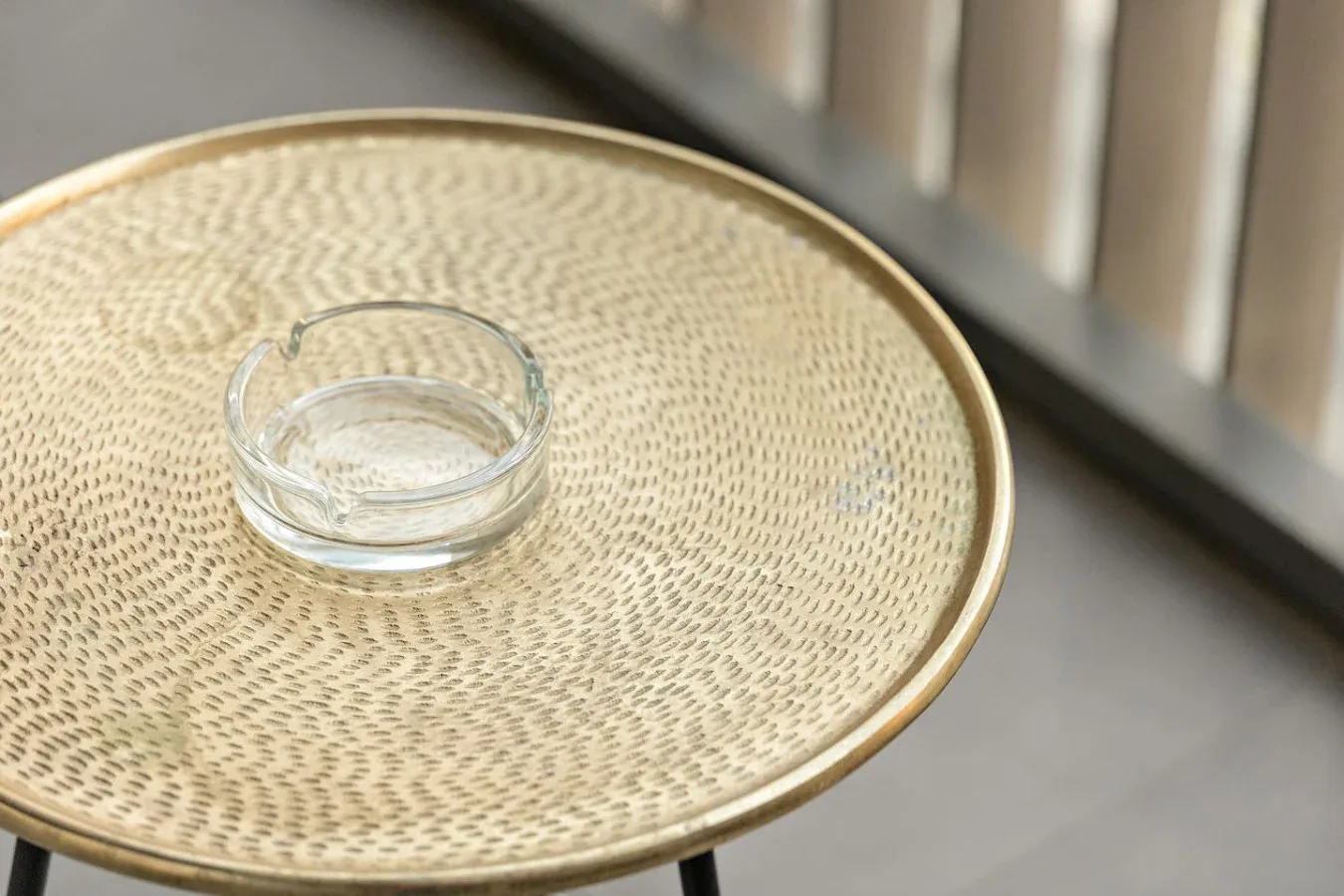 Una mesa redonda pequeña sostiene un cenicero de vidrio transparente.