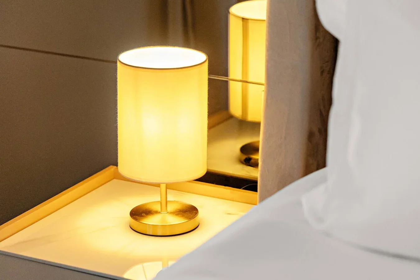 Una lámpara de mesa junto a la cama proyecta una luz cálida.
