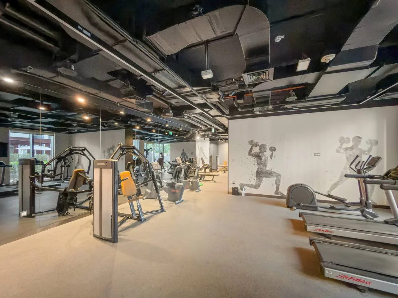 Un gimnasio con máquinas de ejercicio y equipo de entrenamiento distribuido por la sala.