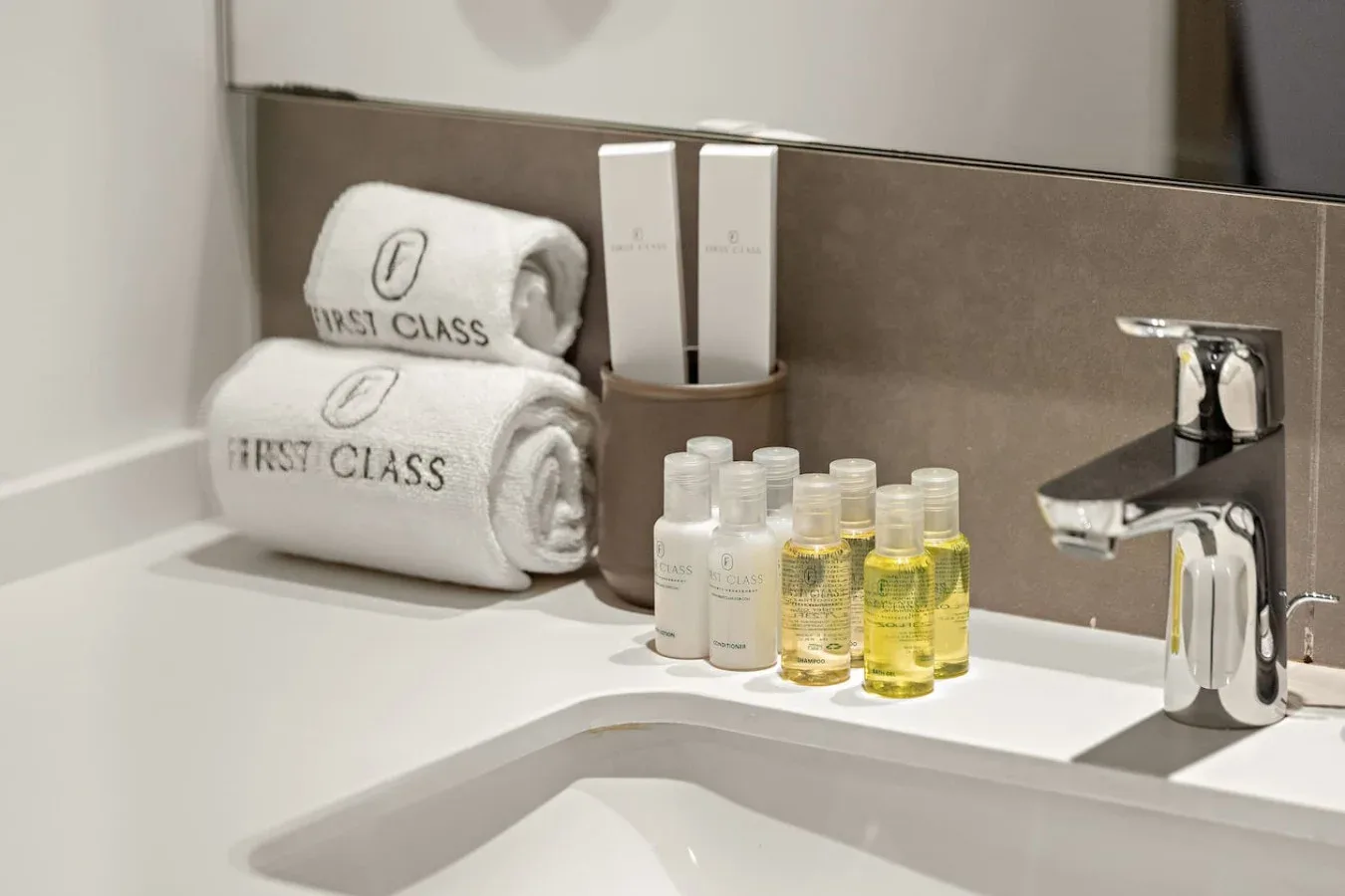 Un lavabo de baño con grifo cromado, artículos de aseo y toallas dobladas.