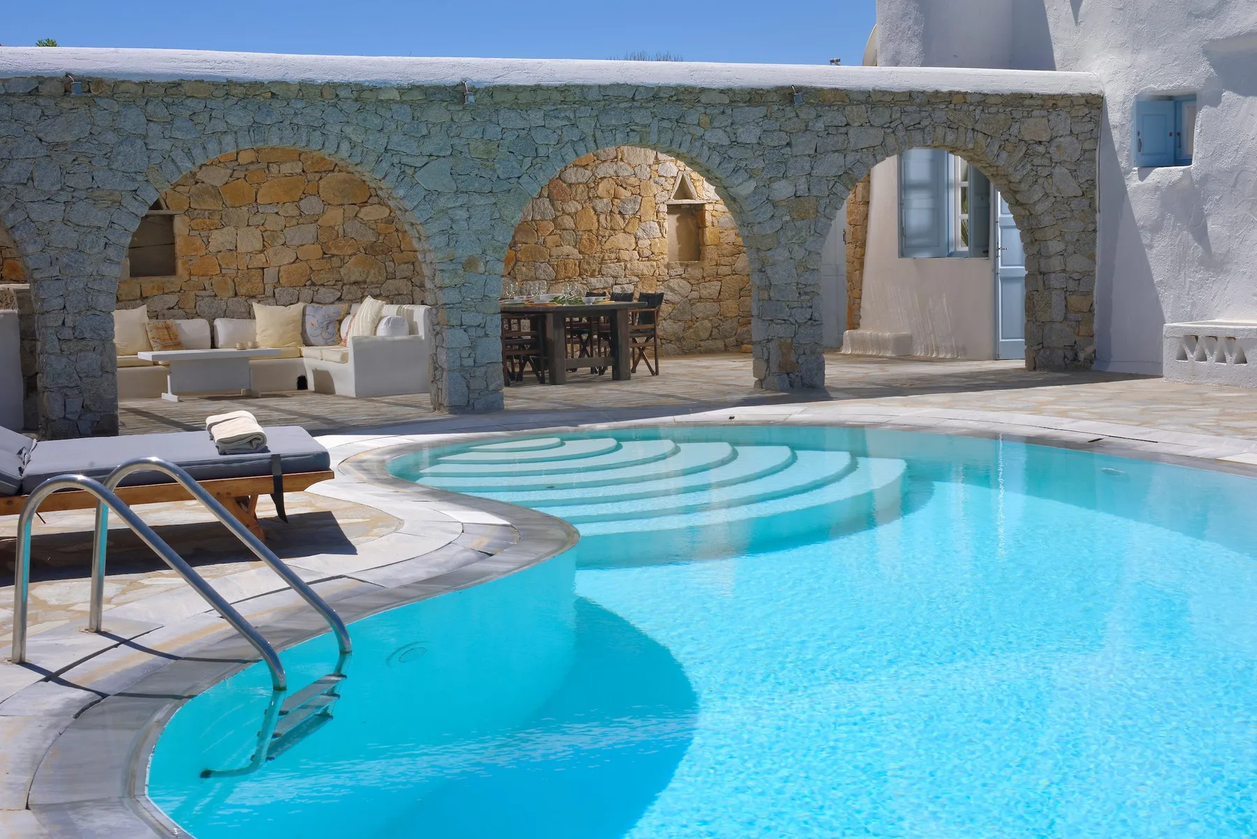 Una piscina frente a una arcada de piedra, con asientos bajo los arcos.