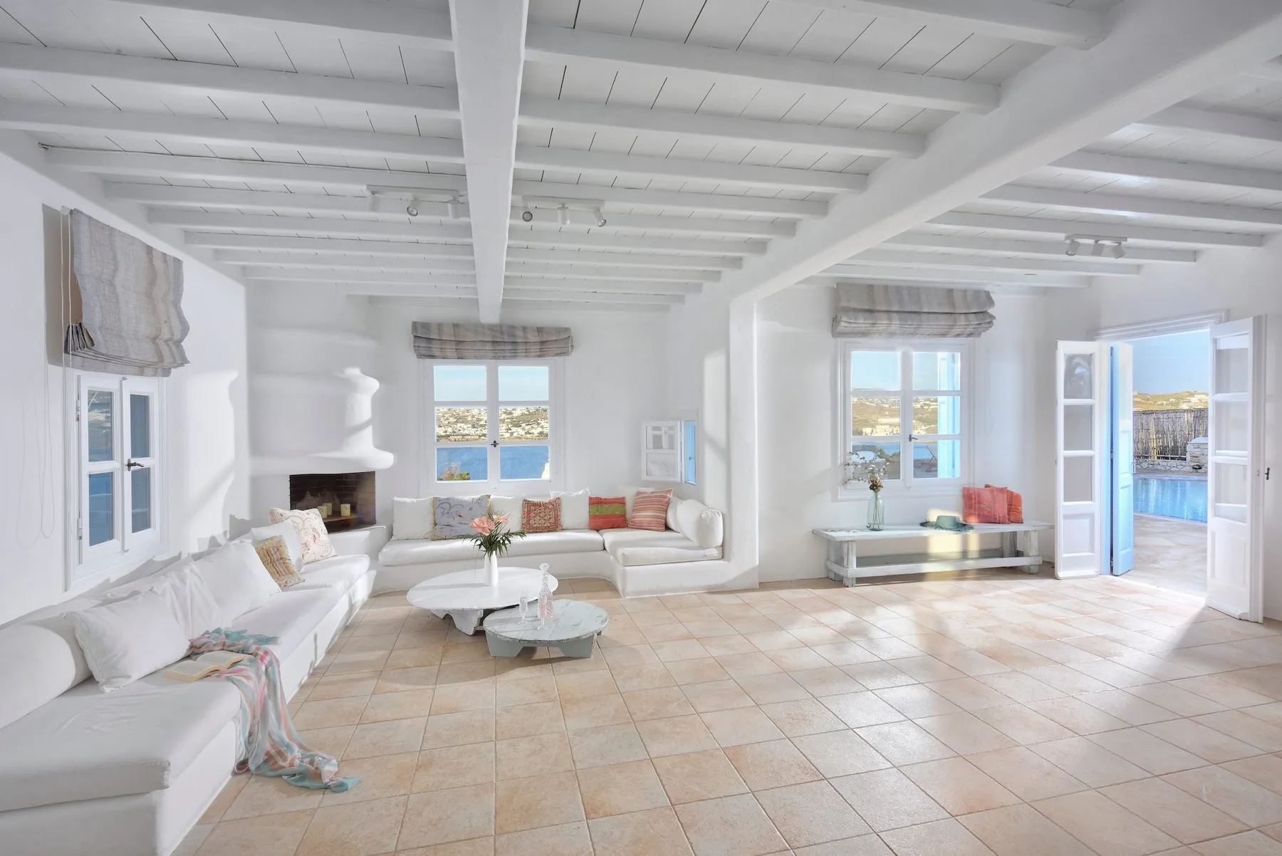 Una sala luminosa con asientos blancos y una puerta abierta hacia la piscina.