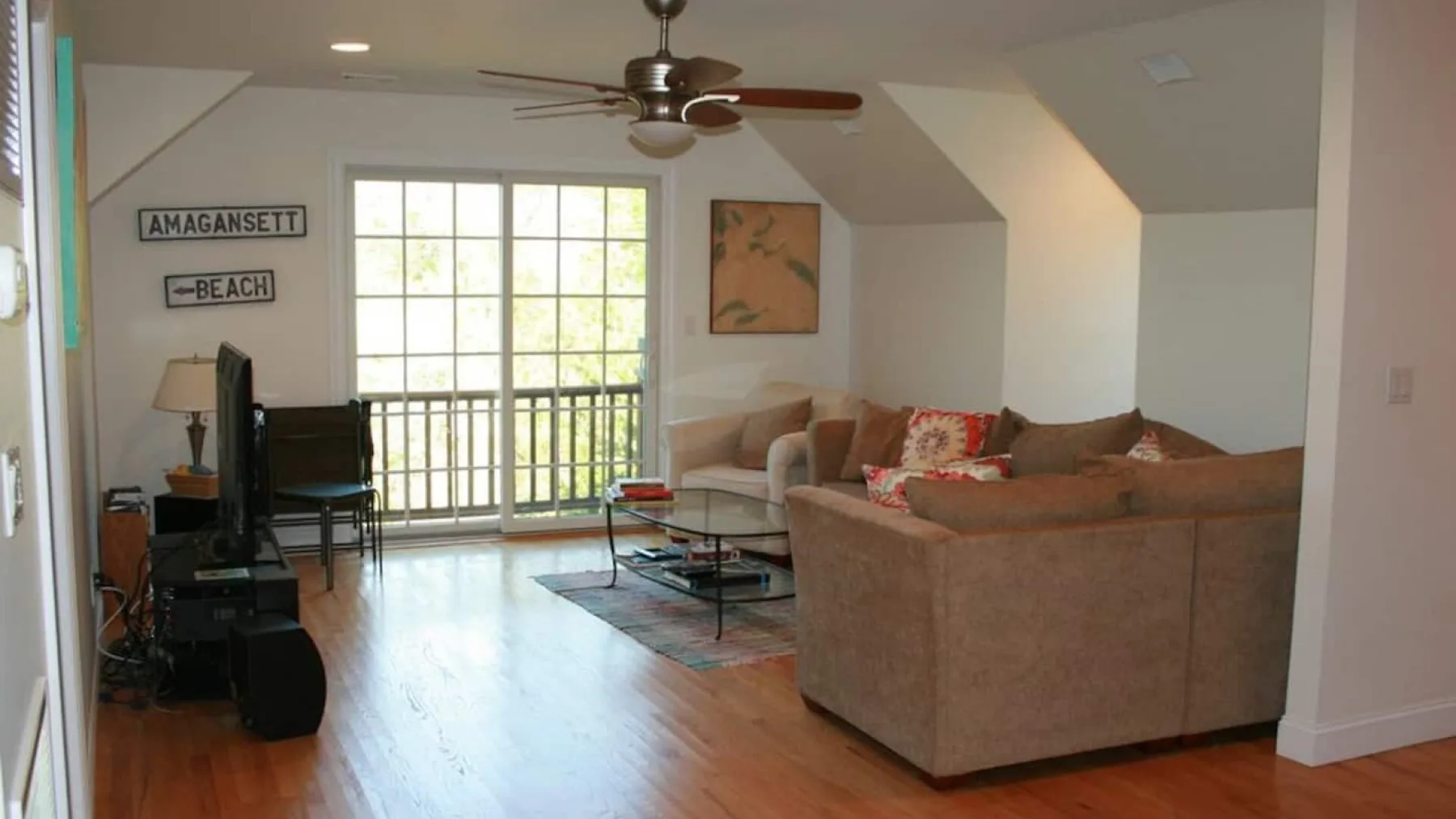 A living room with seating, a coffee table, and glass doors opening onto a balcony.