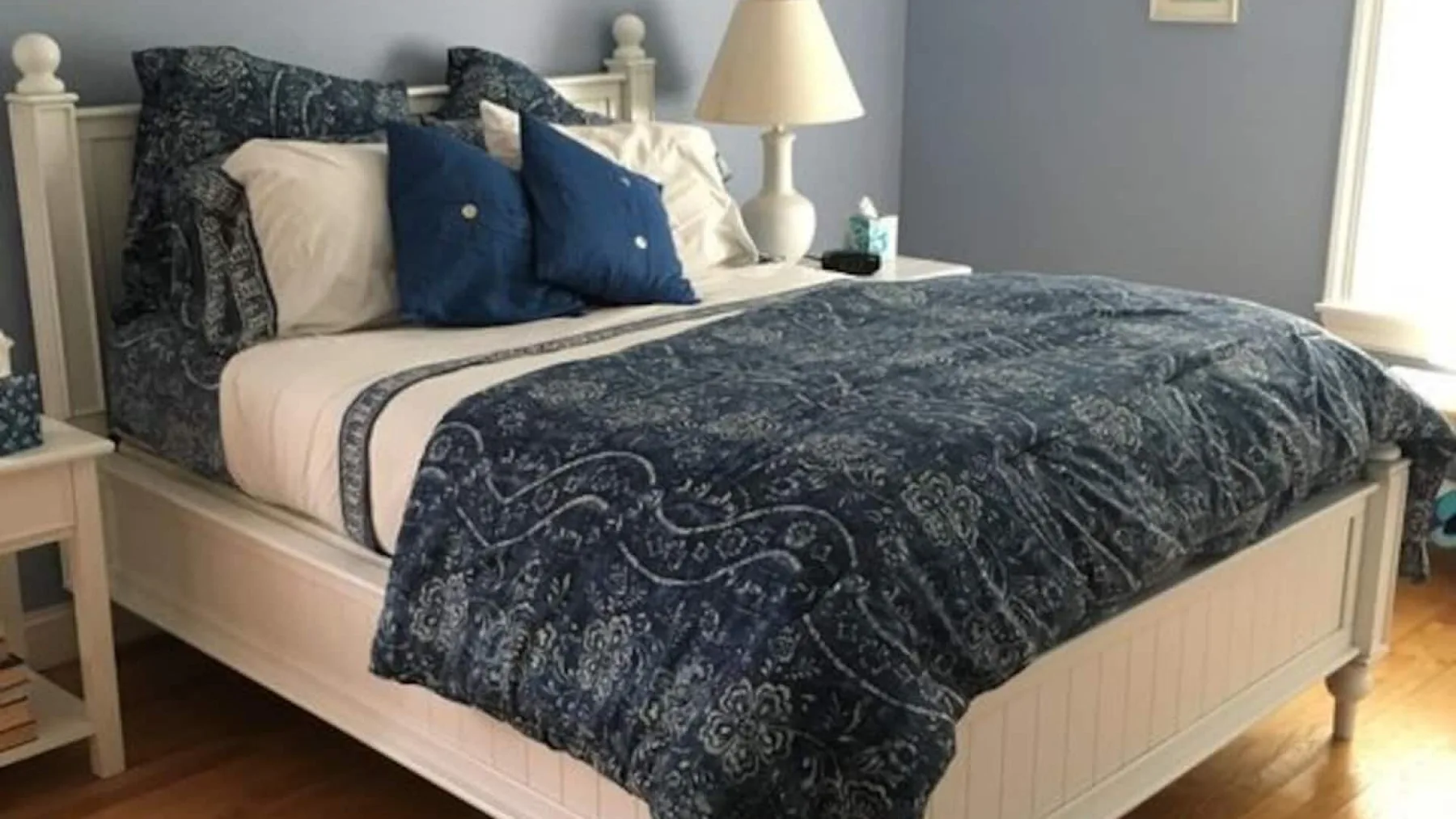 A bedroom with a neatly made bed covered in dark patterned bedding.