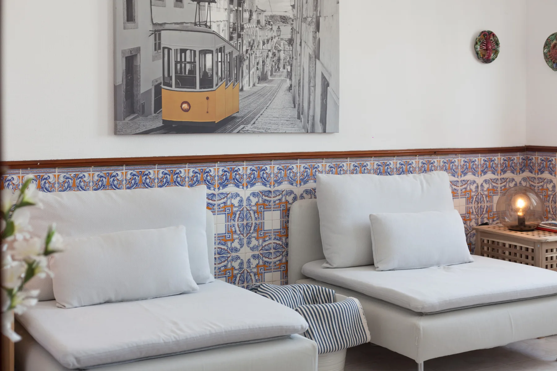 Un dormitorio con dos camas, azulejos estampados y una escena urbana enmarcada.