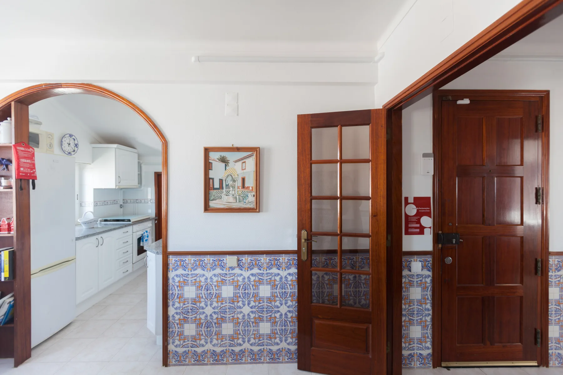 A bright interior hallway connects to a kitchen through an arched opening.