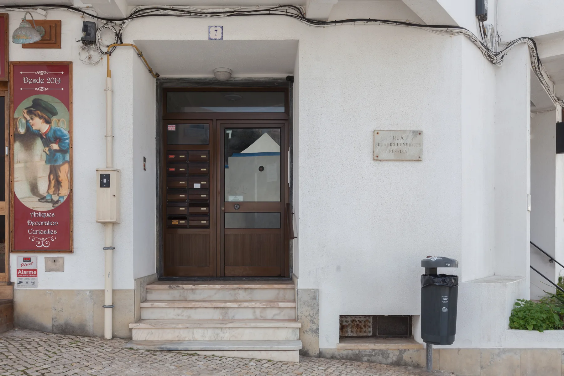 Building entrance with a dark wooden door, mailboxes, and a wall-mounted plaque.