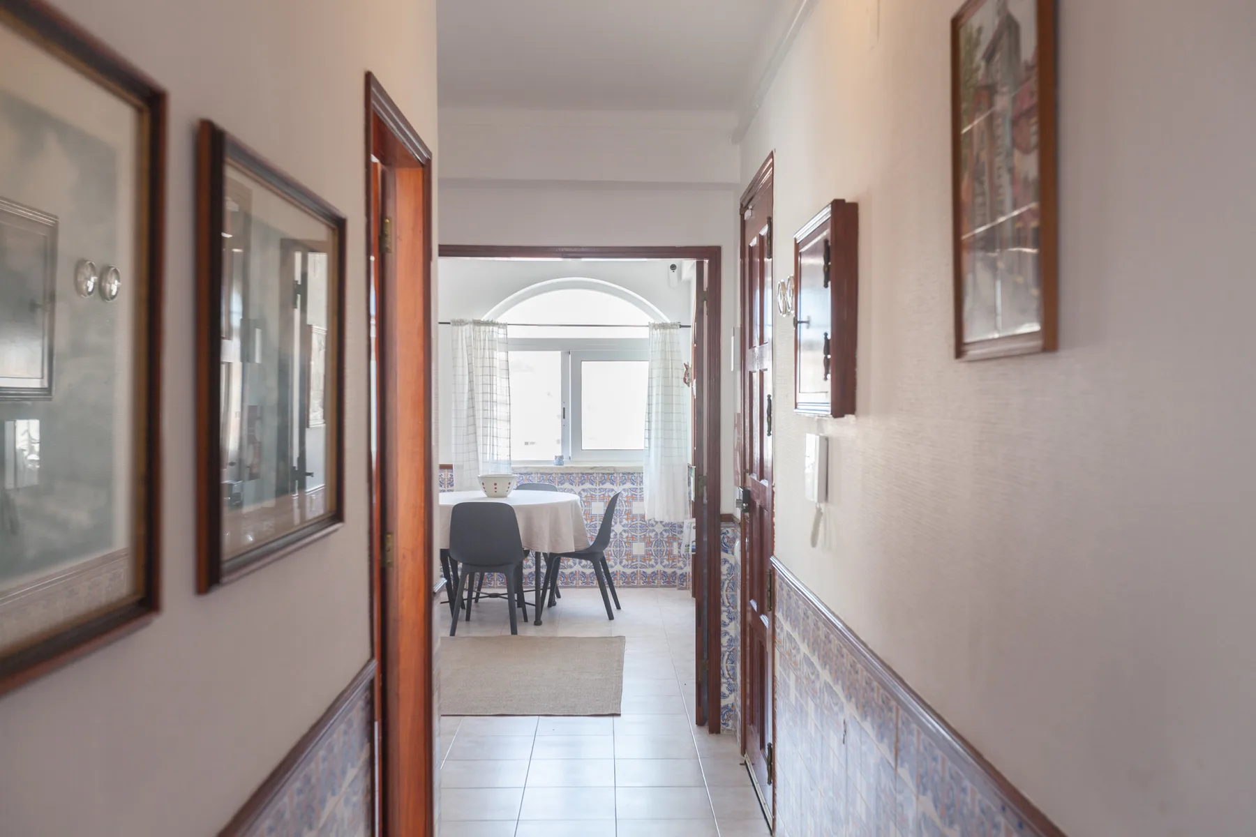 A hallway with framed pictures leads into a dining area.