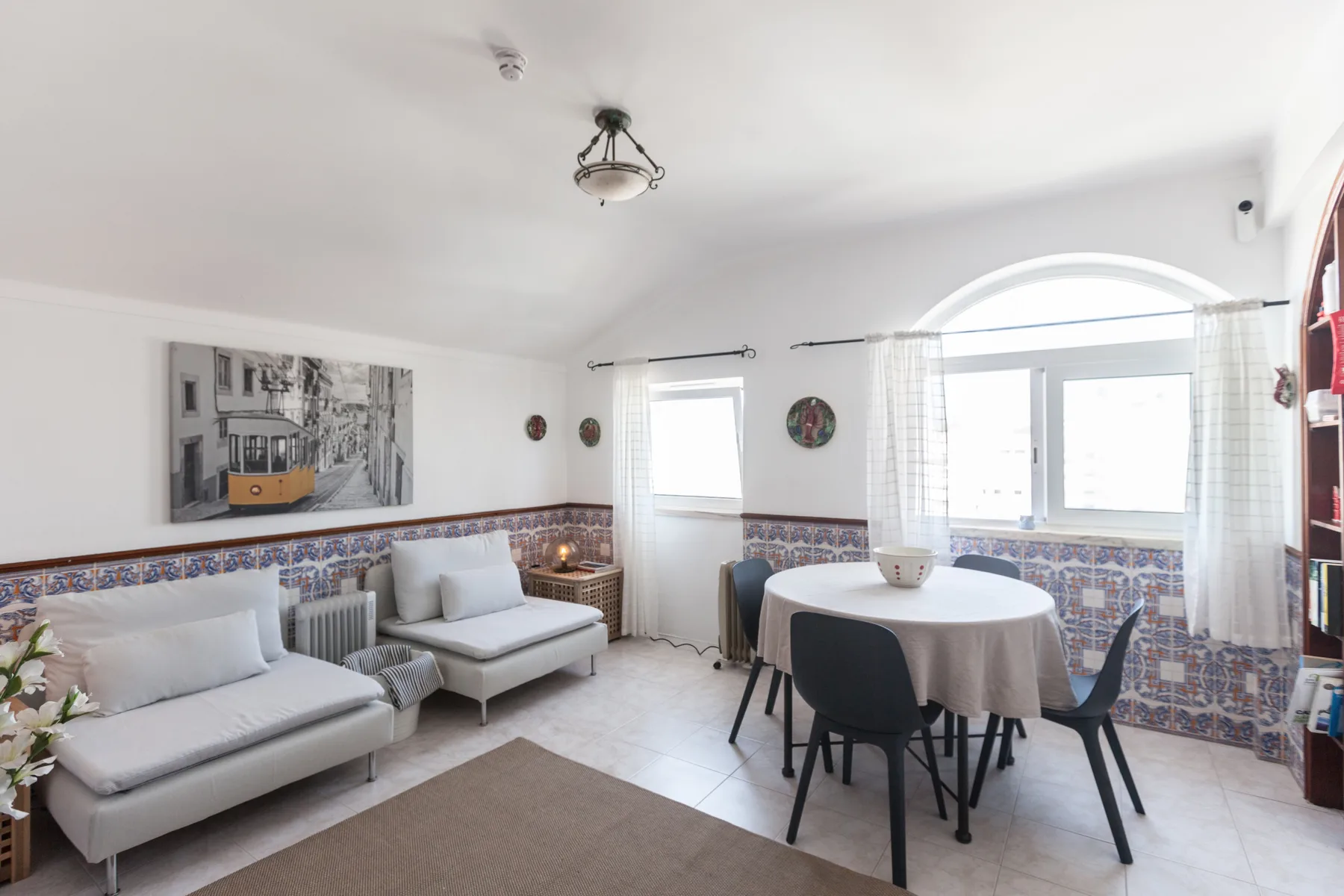 A bright living and dining room with seating, a table, and large windows.