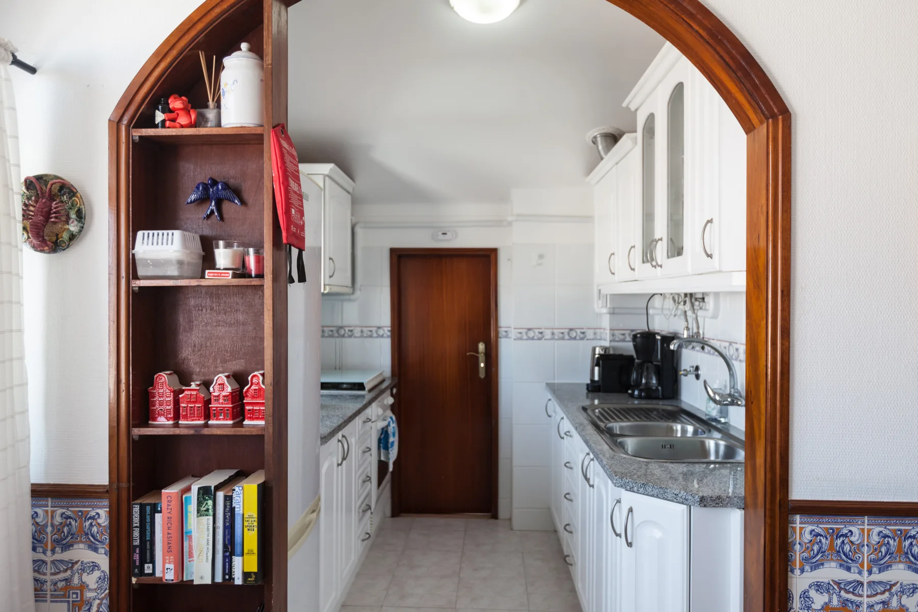 A kitchen with white cabinets, a counter, and a wooden doorway.