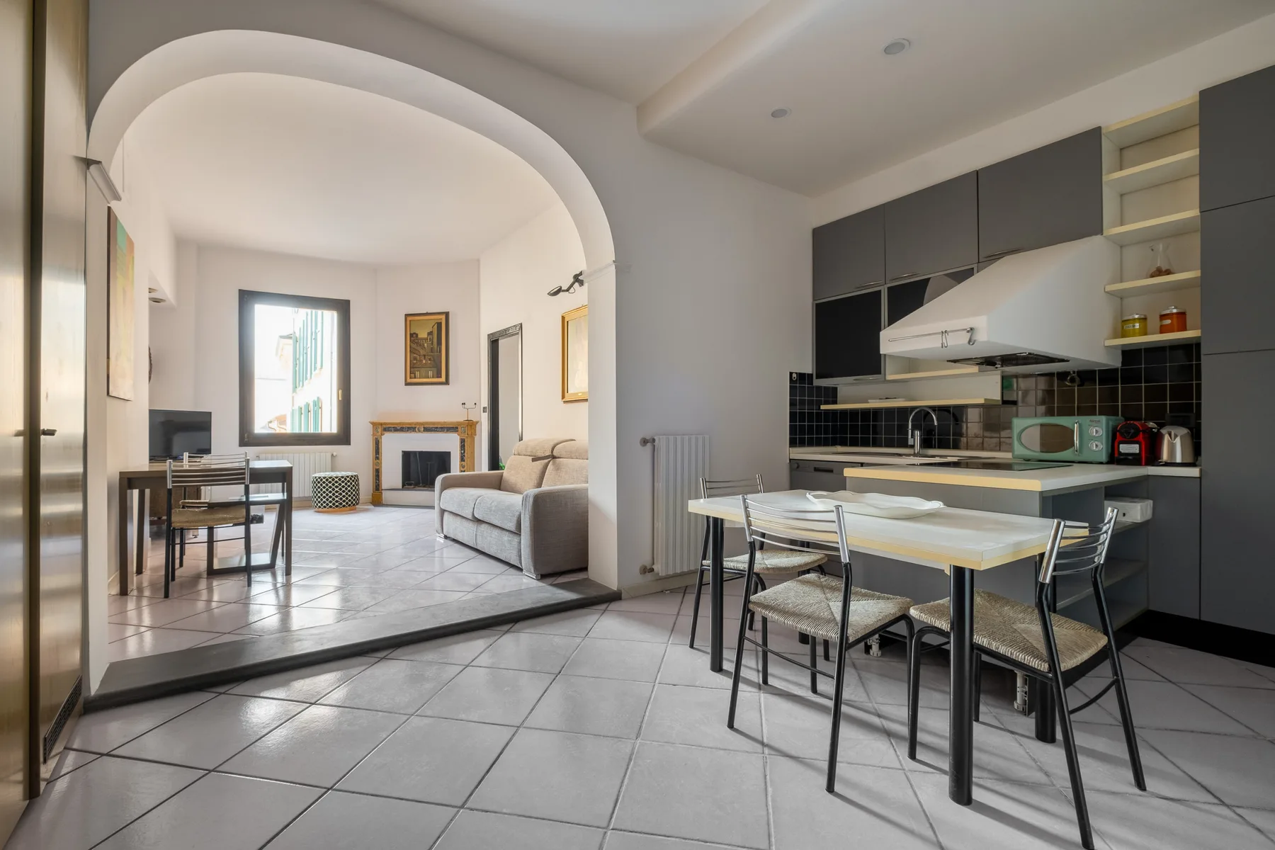 Una cocina y comedor de planta abierta se encuentran junto a una sala de estar, separados por un arco.