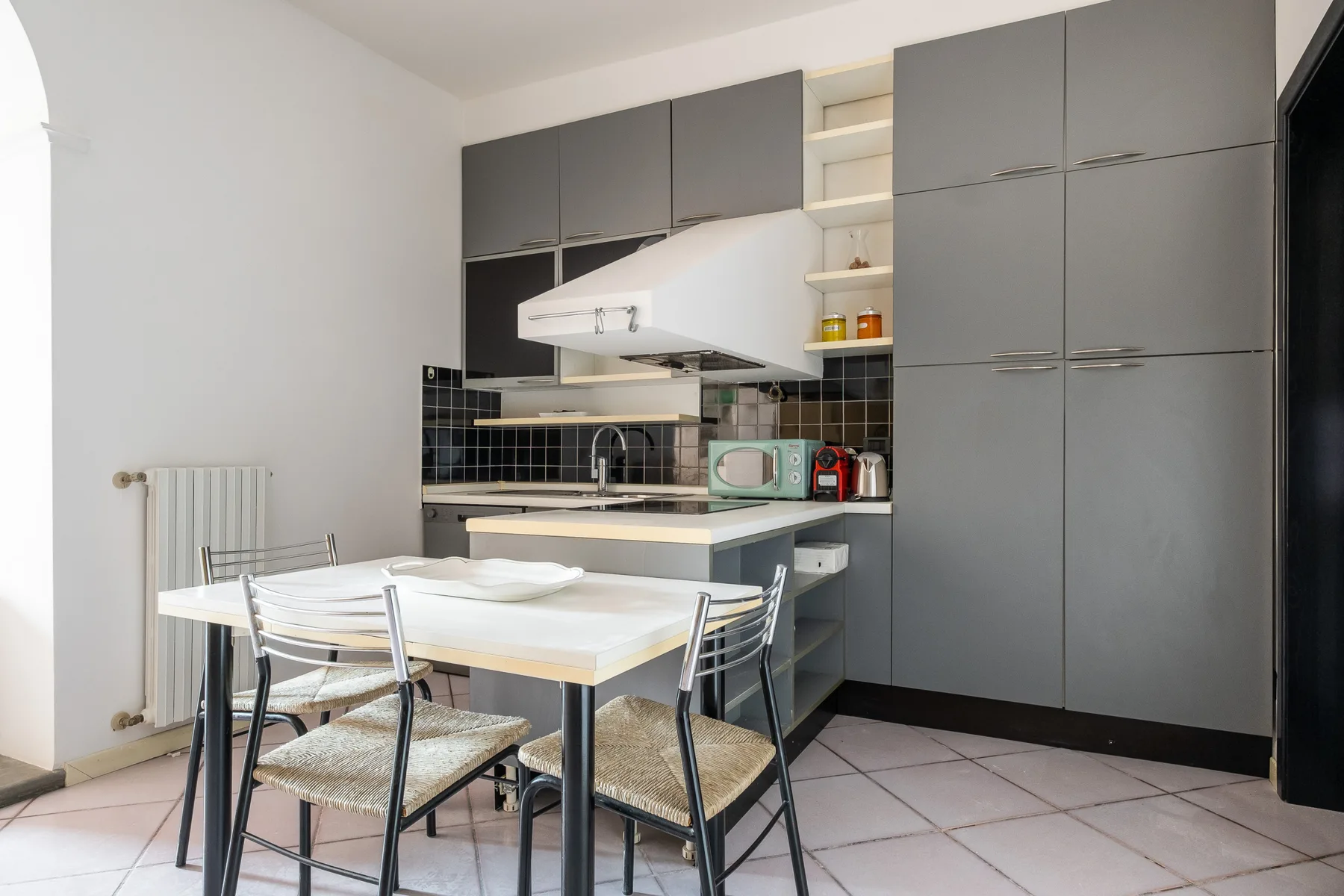 Una cocina moderna con gabinetes grises, una mesa de comedor y pequeños electrodomésticos sobre la encimera.