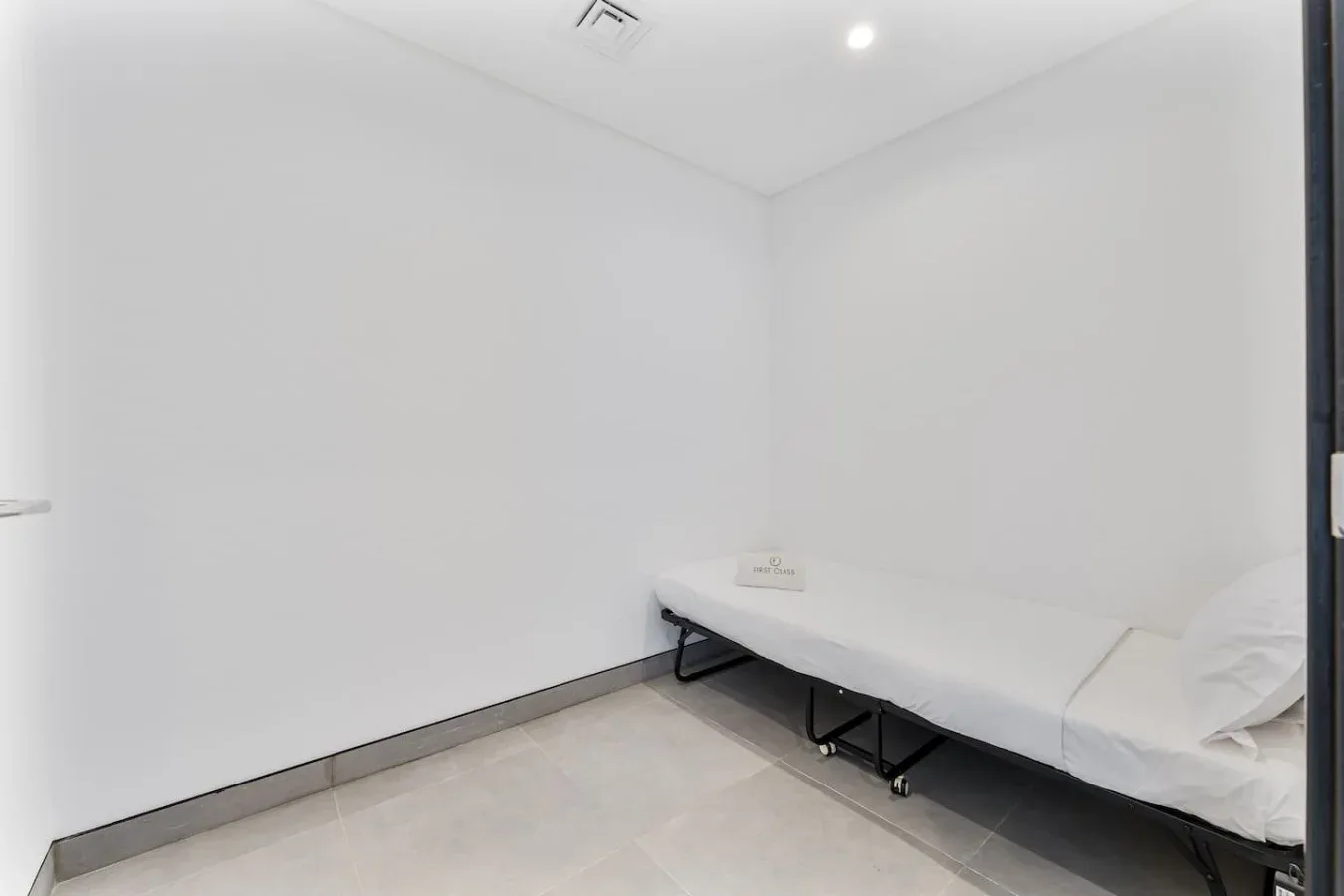 A small bedroom with a bed set against a plain white wall.