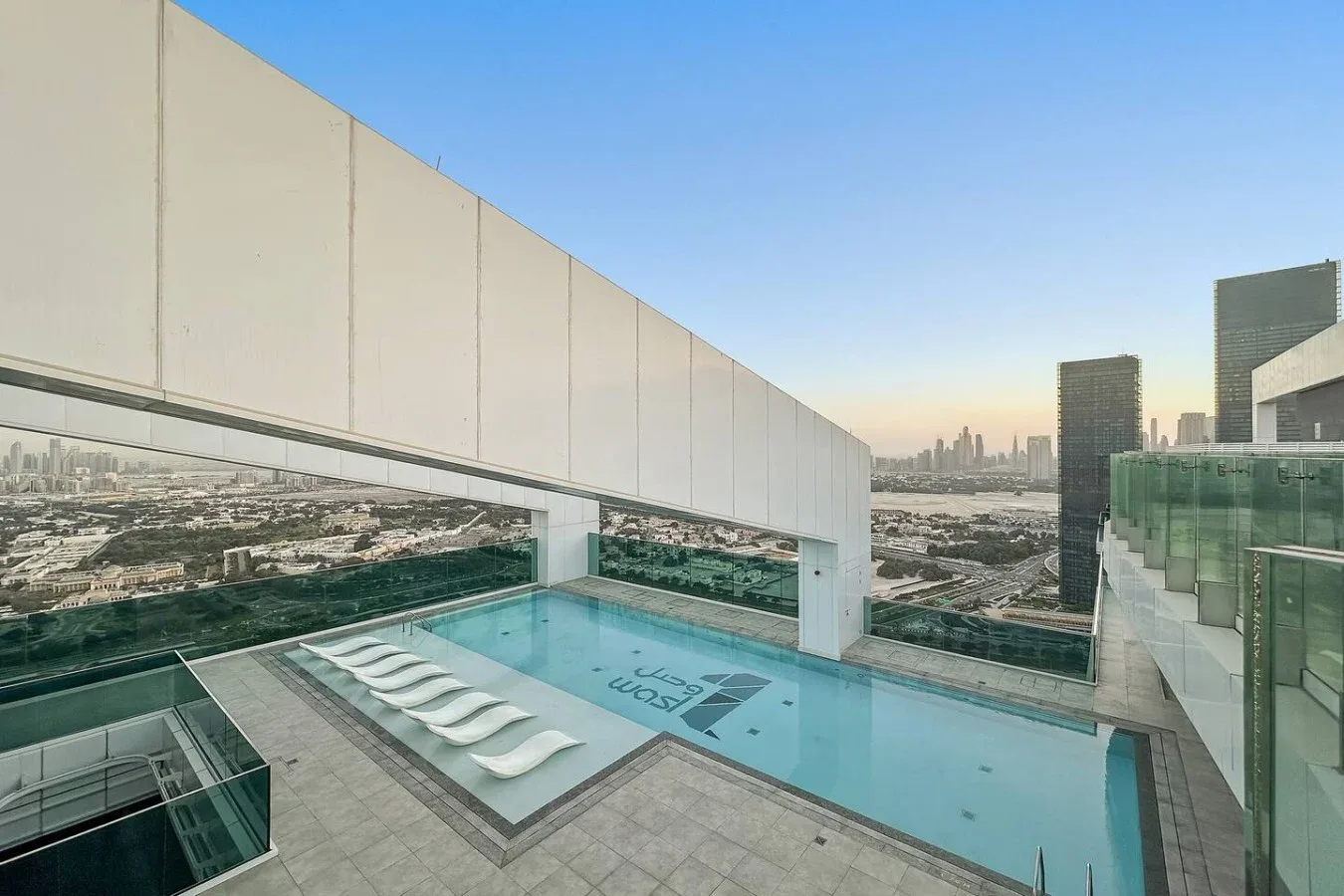 A rooftop swimming pool overlooks the surrounding city skyline.