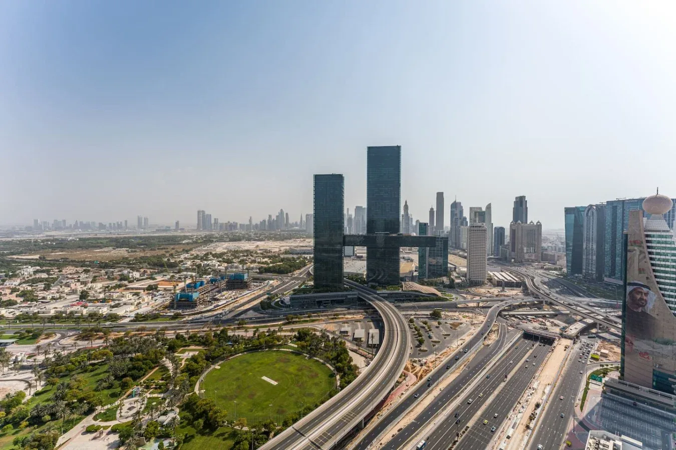 A city skyline rises above multilane roads and curving elevated highways.