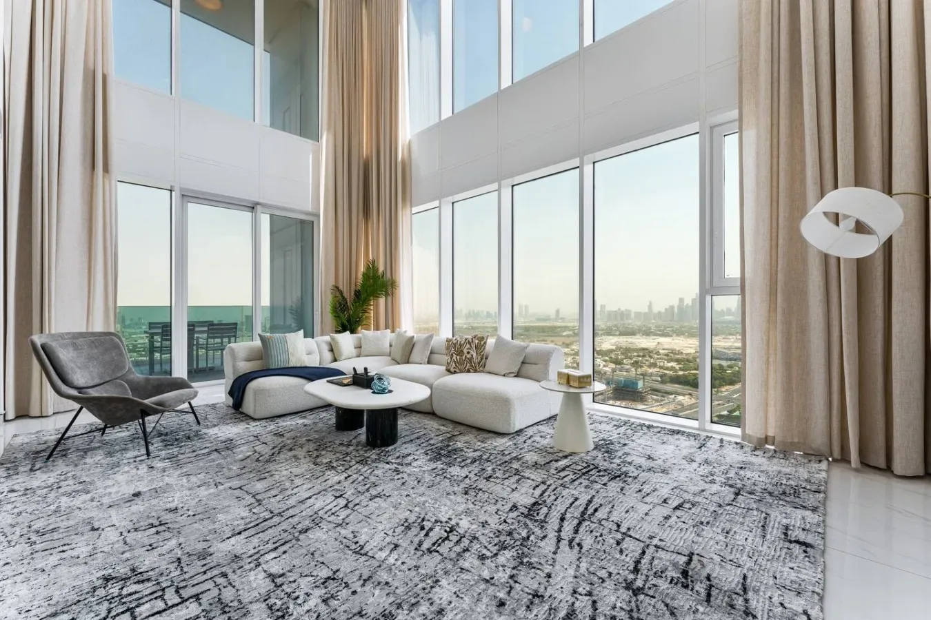 A bright living room with large windows and seating overlooking the city.