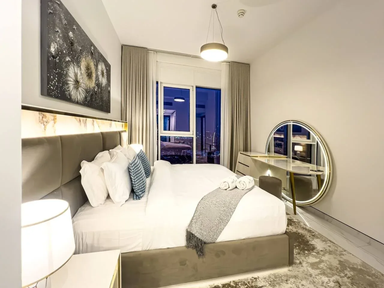 A bedroom with a large bed, bedside lamp, and glass doors opening onto a balcony.