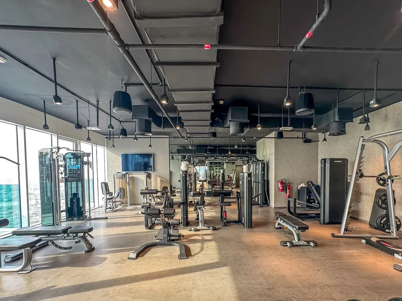 A gym with workout machines and weights arranged across an open exercise area.
