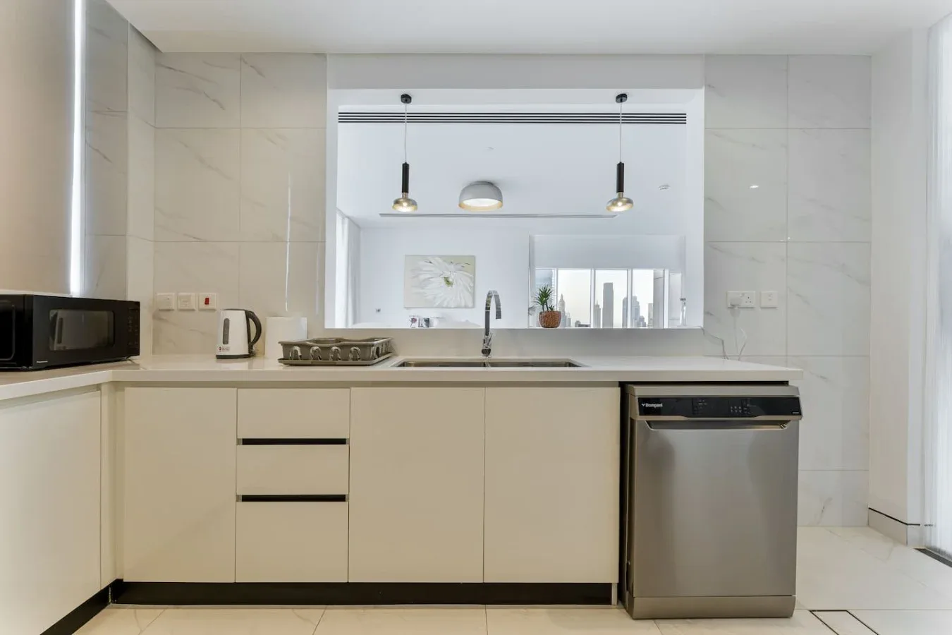 A bright modern kitchen with white cabinetry, a countertop, and a stainless steel dishwasher.