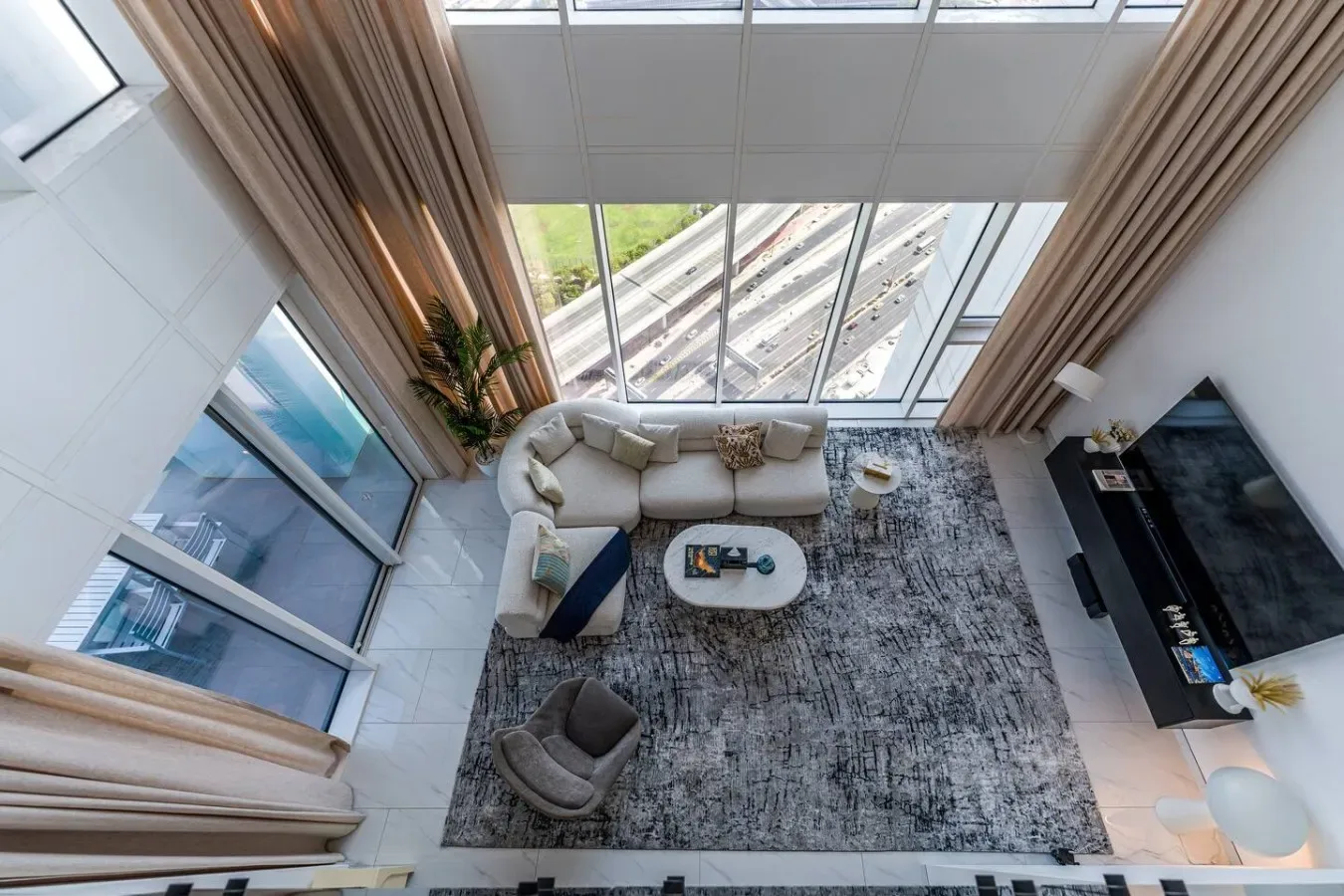 A bright living room with seating, a rug, and floor-to-ceiling windows.