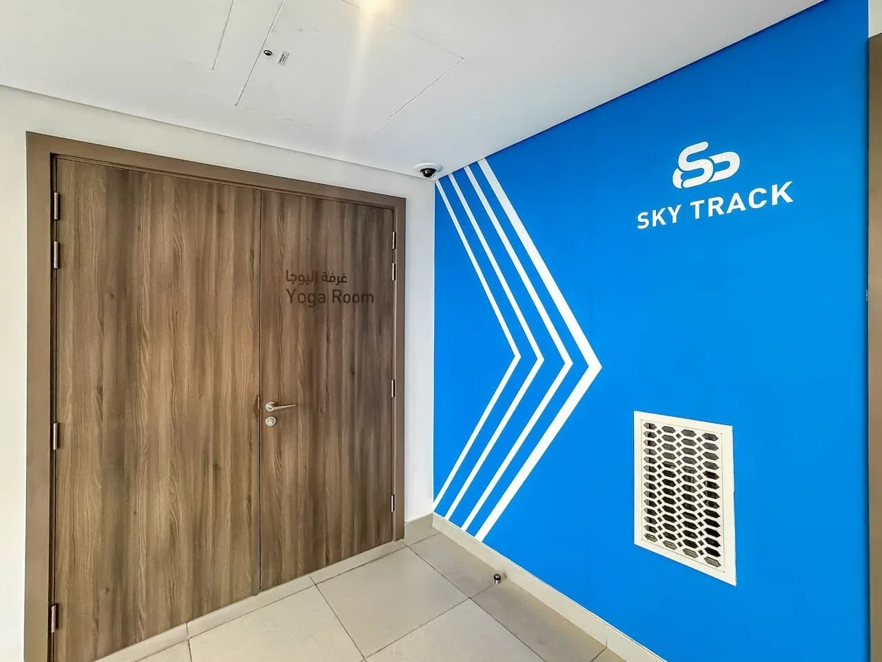 A blue hallway wall with a wooden door and white directional graphics.