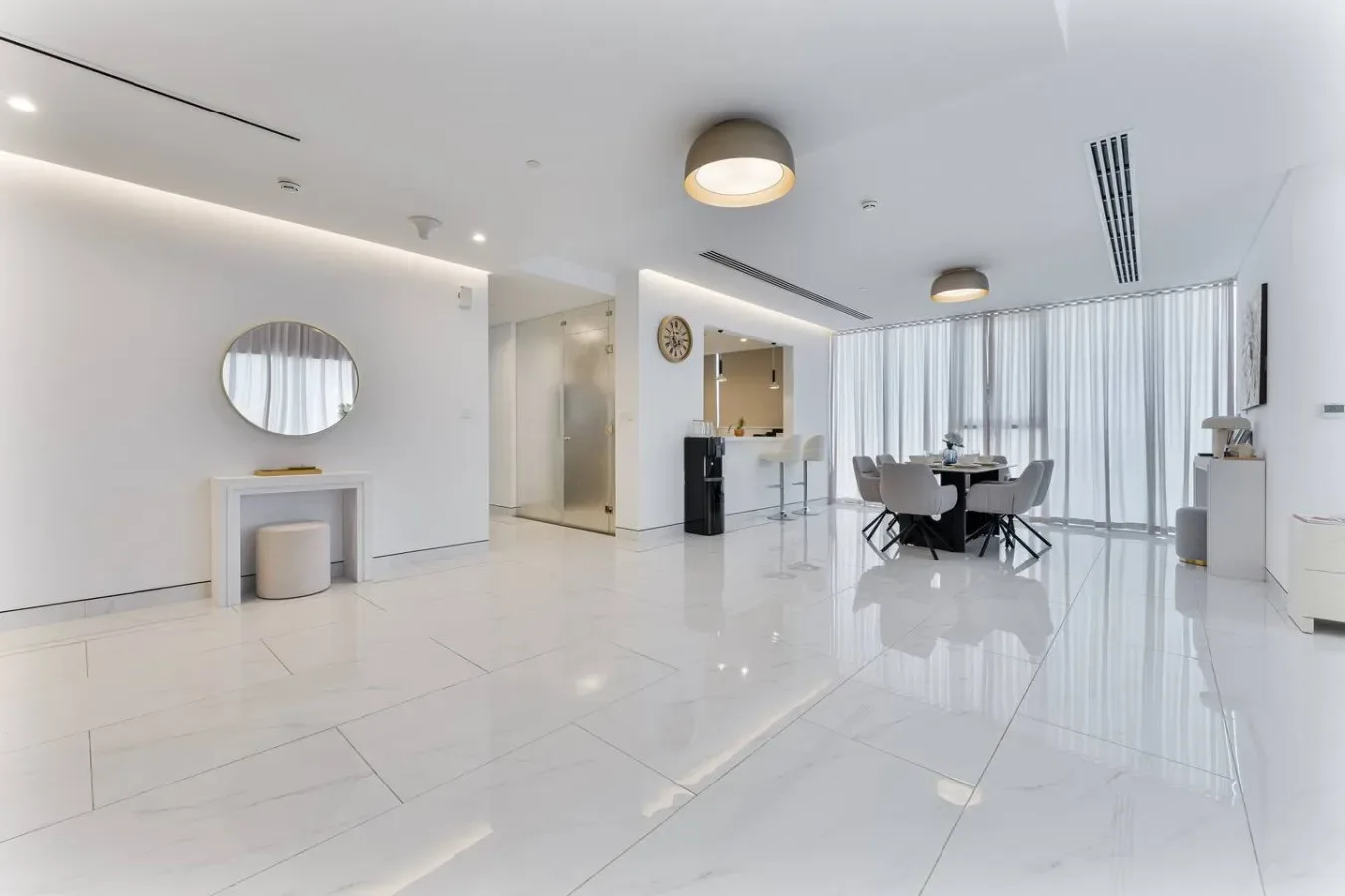 A bright open-plan dining area with a table and floor-to-ceiling curtains.
