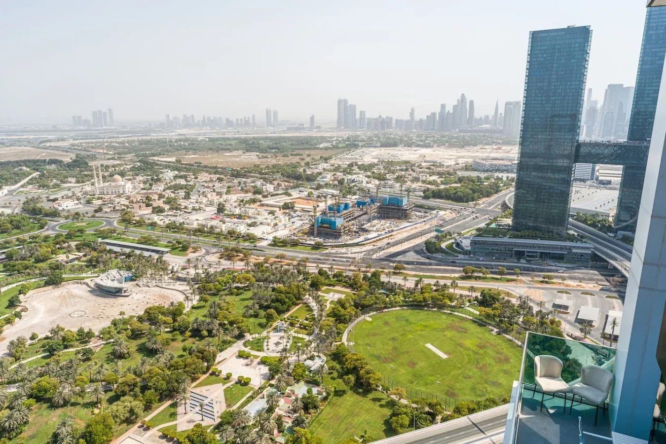 Aerial cityscape with a green park and high-rise buildings in the distance.