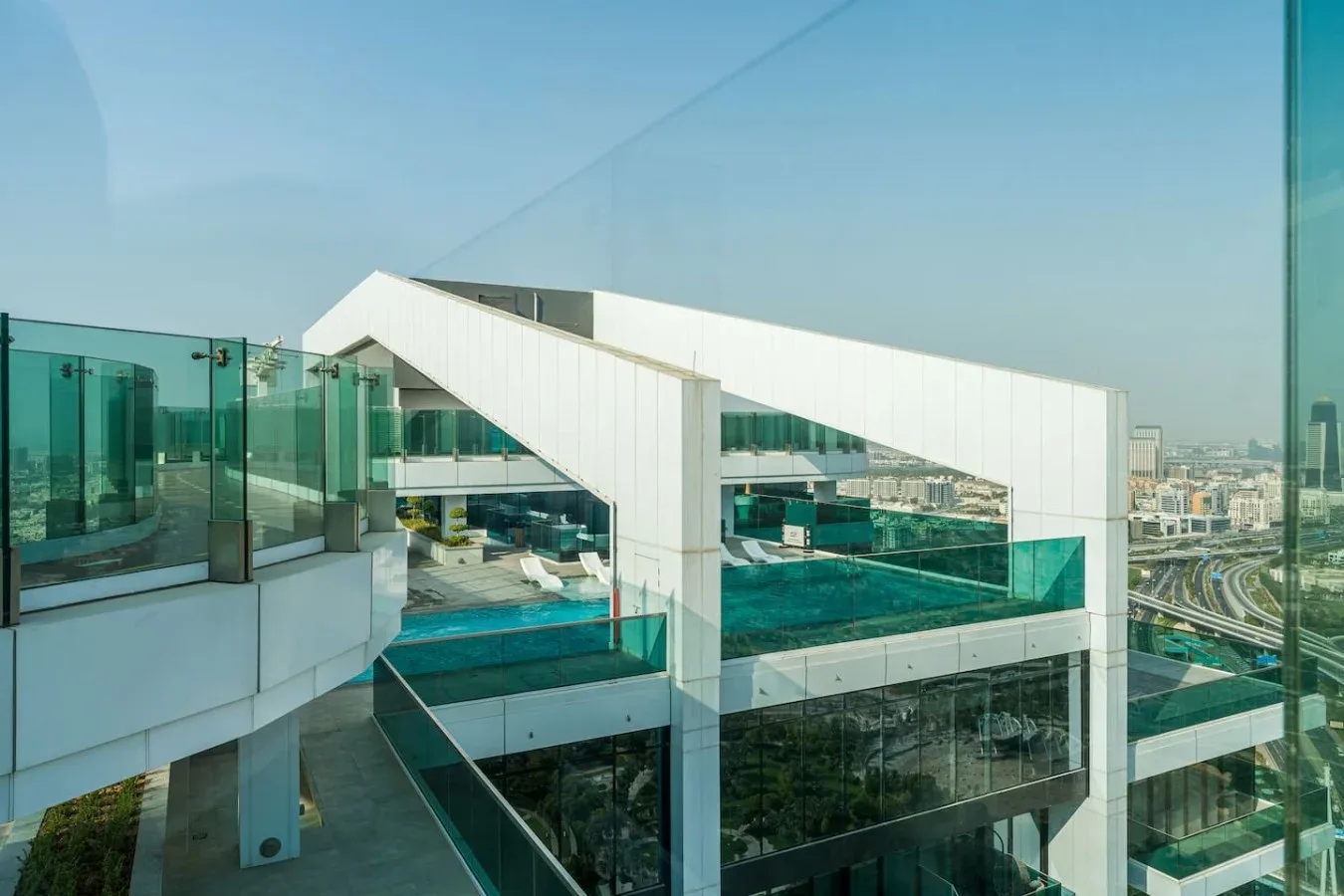 A rooftop terrace with a swimming pool and glass railings overlooks the city.