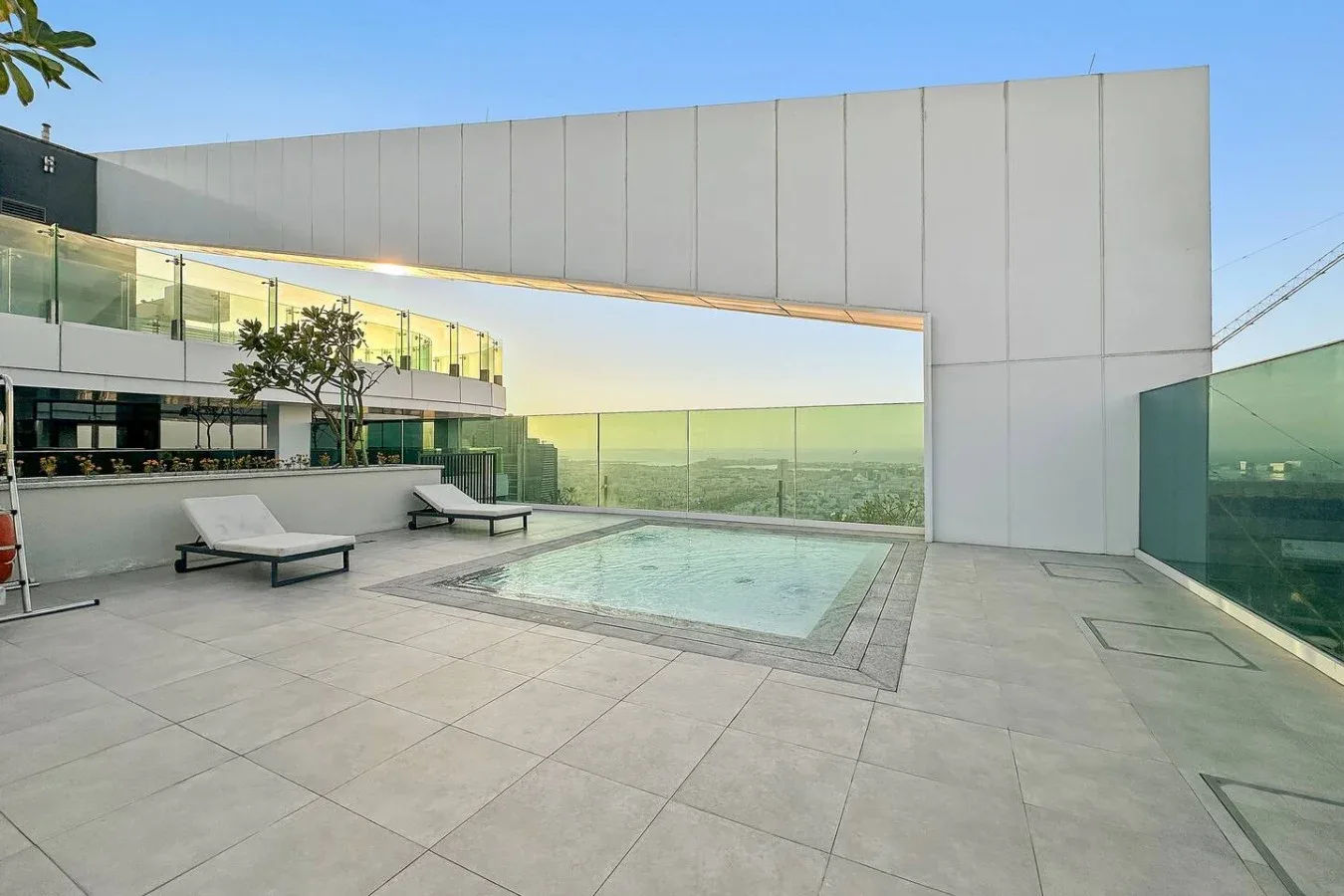 A rooftop terrace with a swimming pool and lounge seating overlooks the surrounding city.