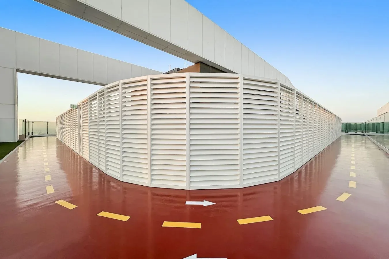 A rooftop walkway curves around a large white louvered structure.