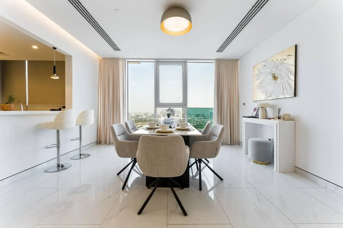 A bright dining area with a table and seating beside large windows.