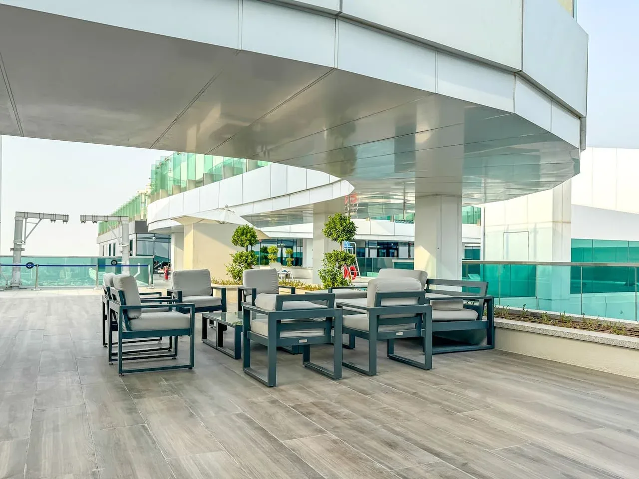 An outdoor terrace seating area beneath a modern overhang, with glass railings.