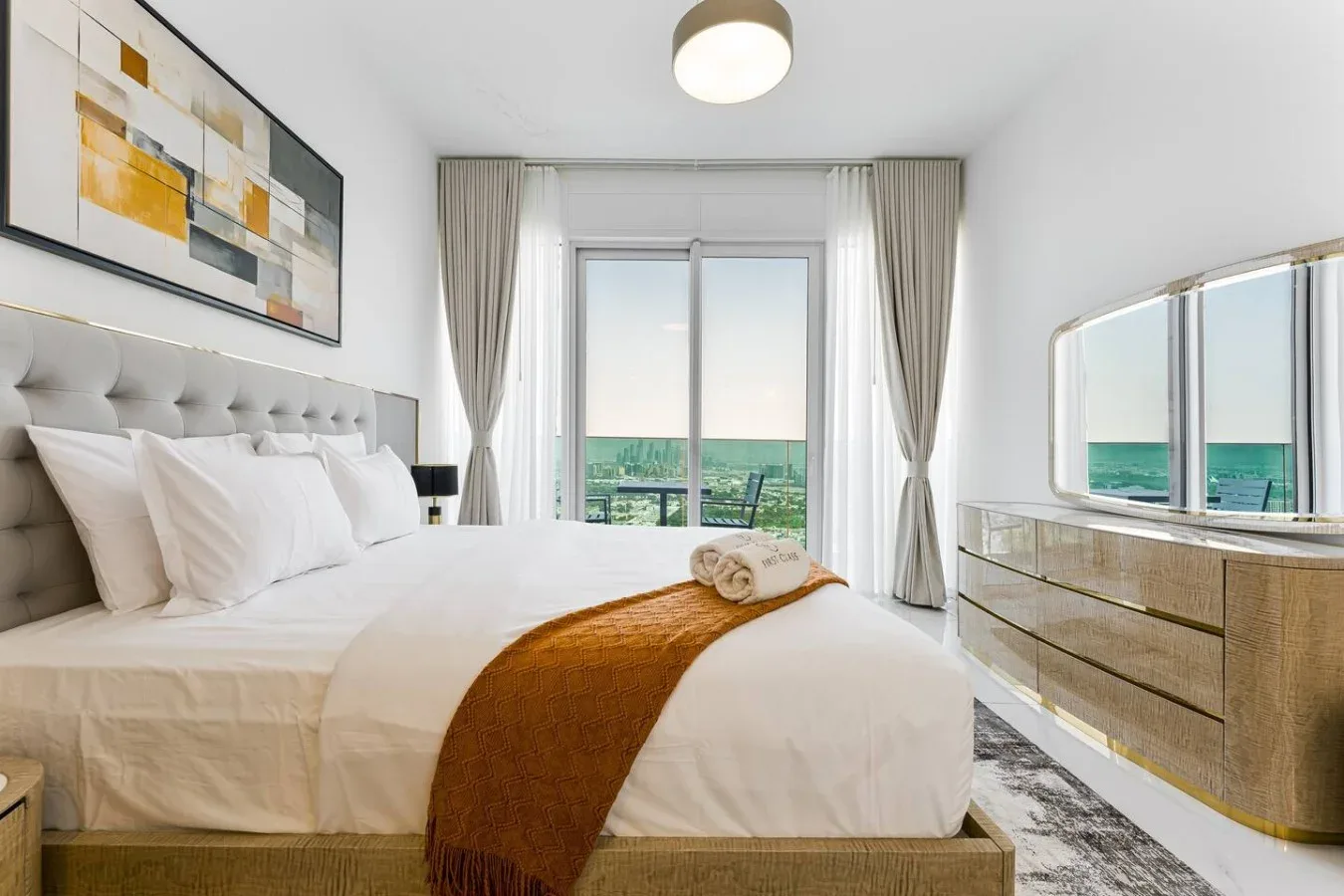 A bright bedroom with a neatly made bed and ocean views through the windows.