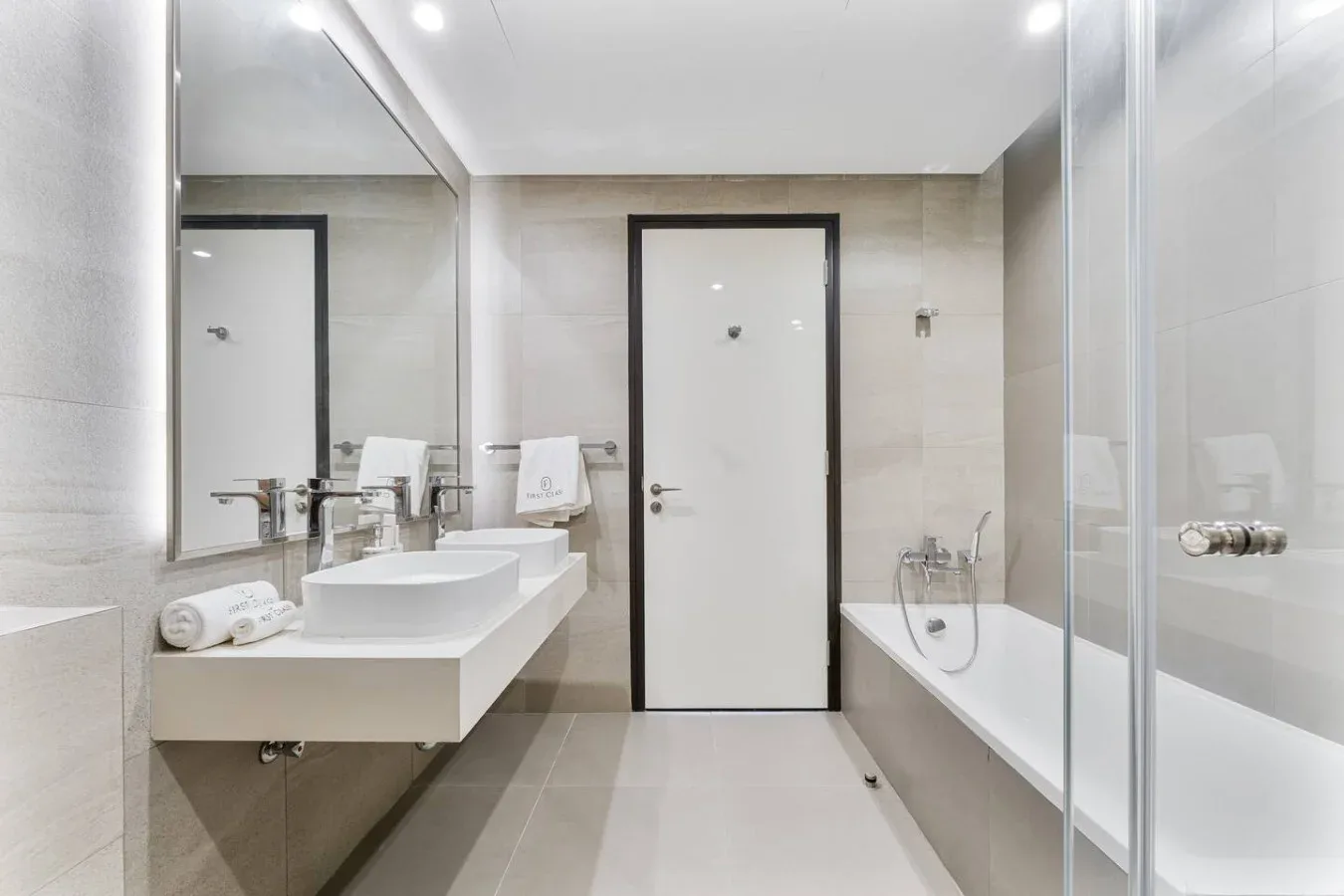 A bright bathroom with a sink, large mirror, and bathtub.
