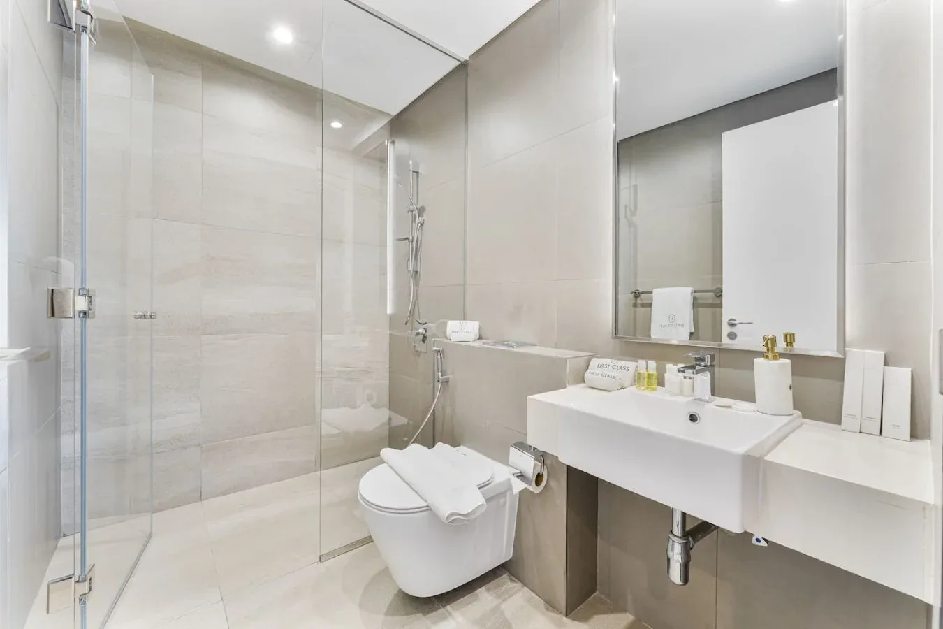 A bright tiled bathroom with a glass shower and a wall-mounted sink.