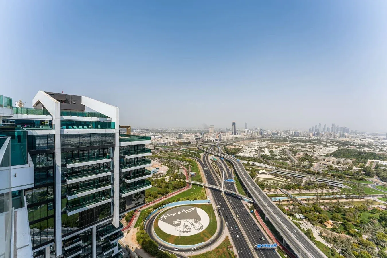 A city skyline and elevated highways extend beside a modern glass office building.