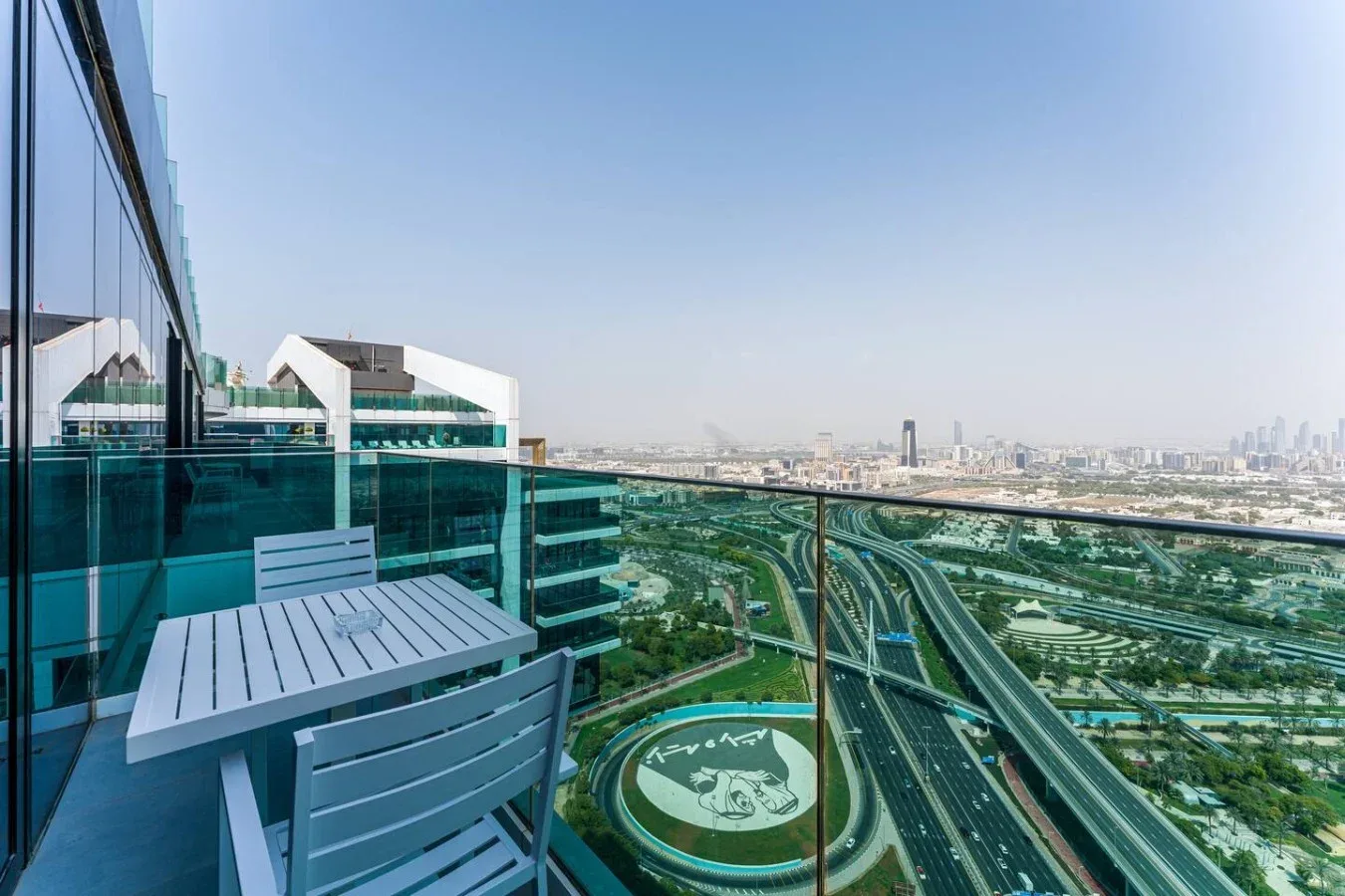 A balcony seating area overlooks a multilane highway and the distant city skyline.