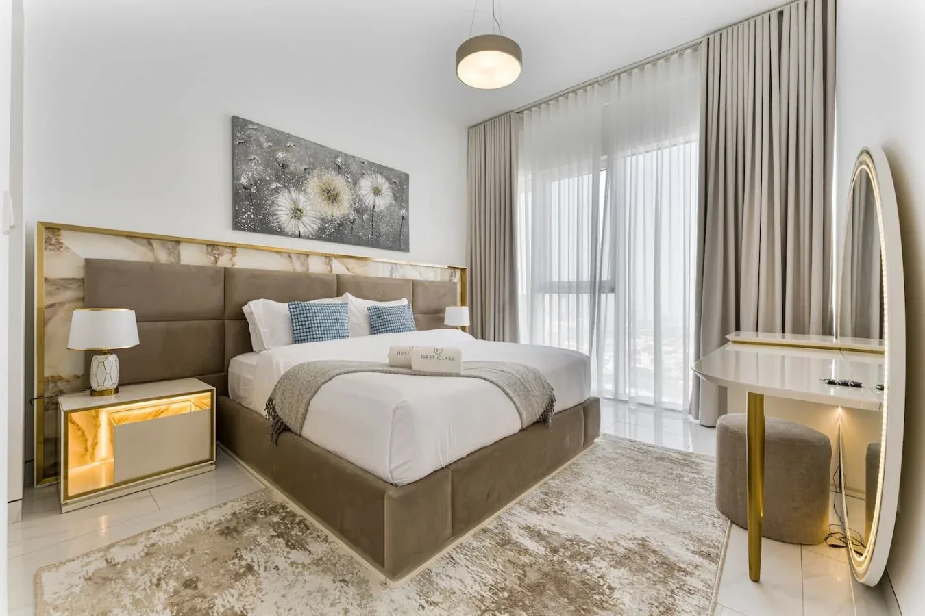 A bedroom with a bed, bedside tables, and tall curtained windows.