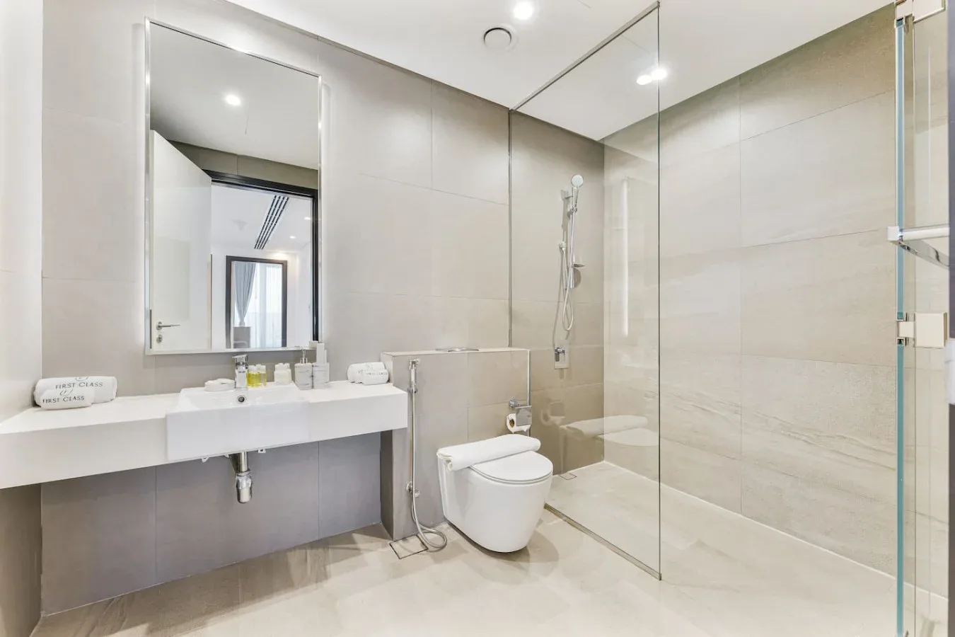 A modern bathroom with a long sink counter and a glass shower.