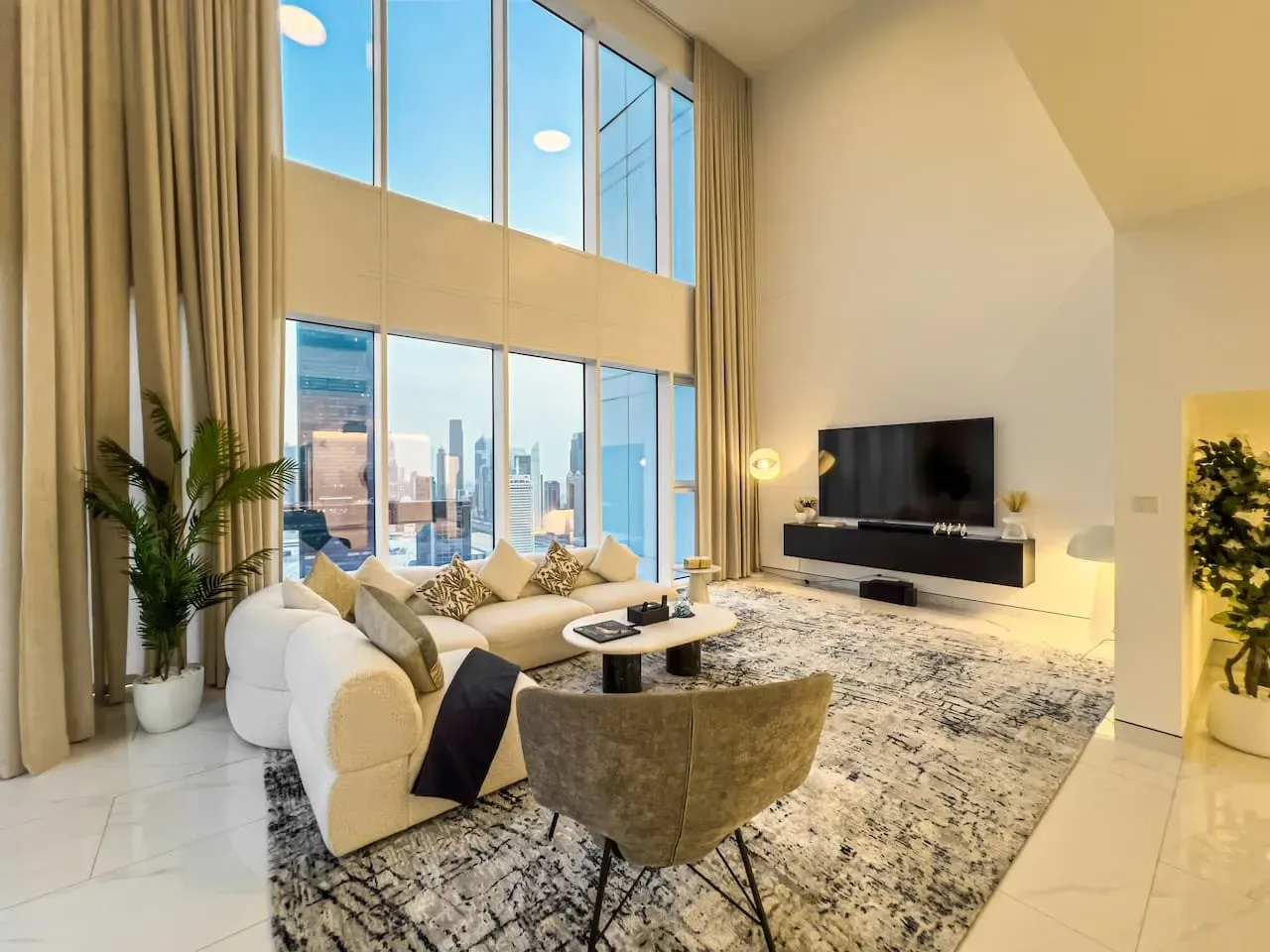 A bright double-height living room has large windows overlooking the city.