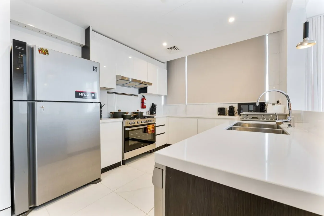 A bright modern kitchen with white counters and stainless steel appliances.